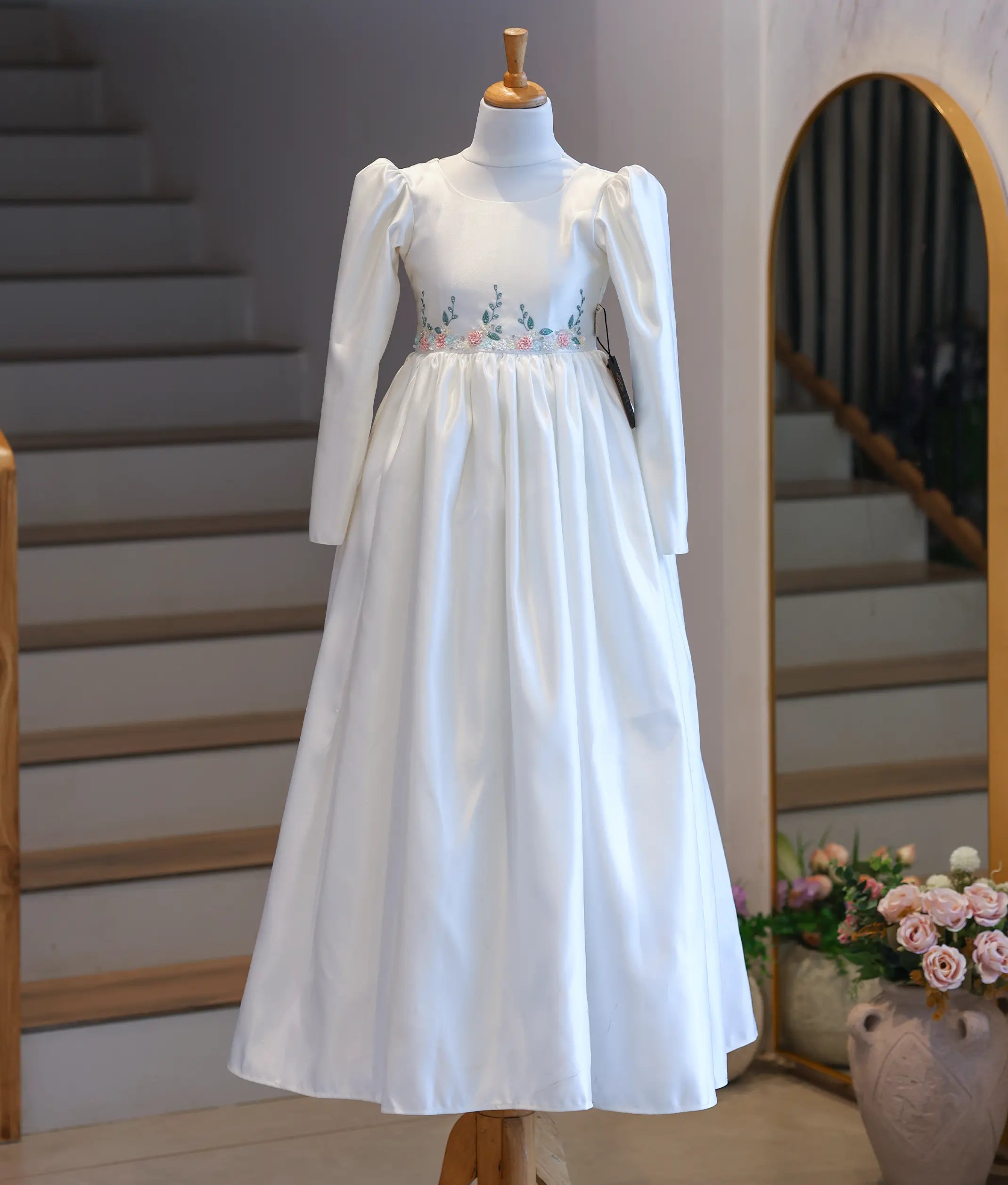 Full-length front view of the long-sleeve off-white satin Holy Communion dress displayed on a mannequin.