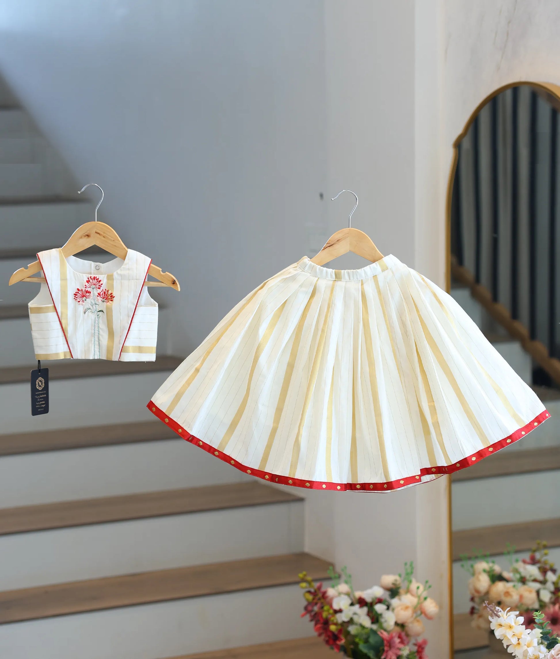 Front view of a traditional off-white and golden Kasavu skirt and top set with red borders.