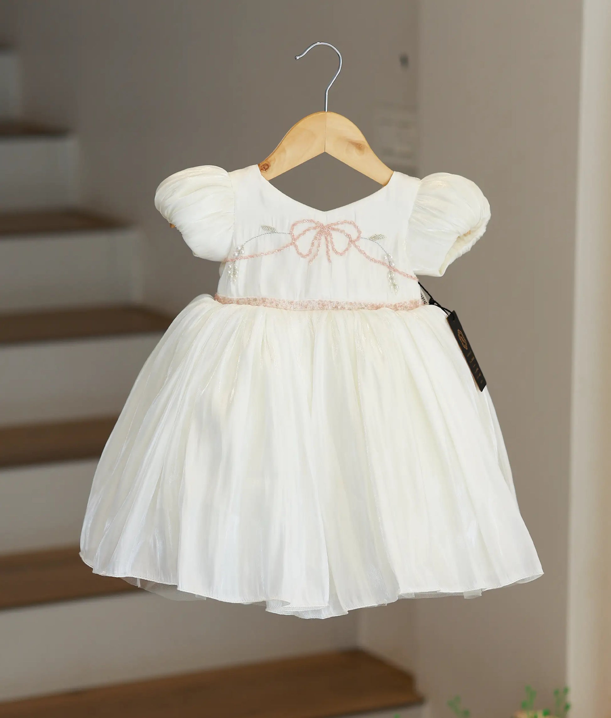 Full front view of an off-white laser organza party frock for baby girls featuring puffed sleeves and a pleated skirt.