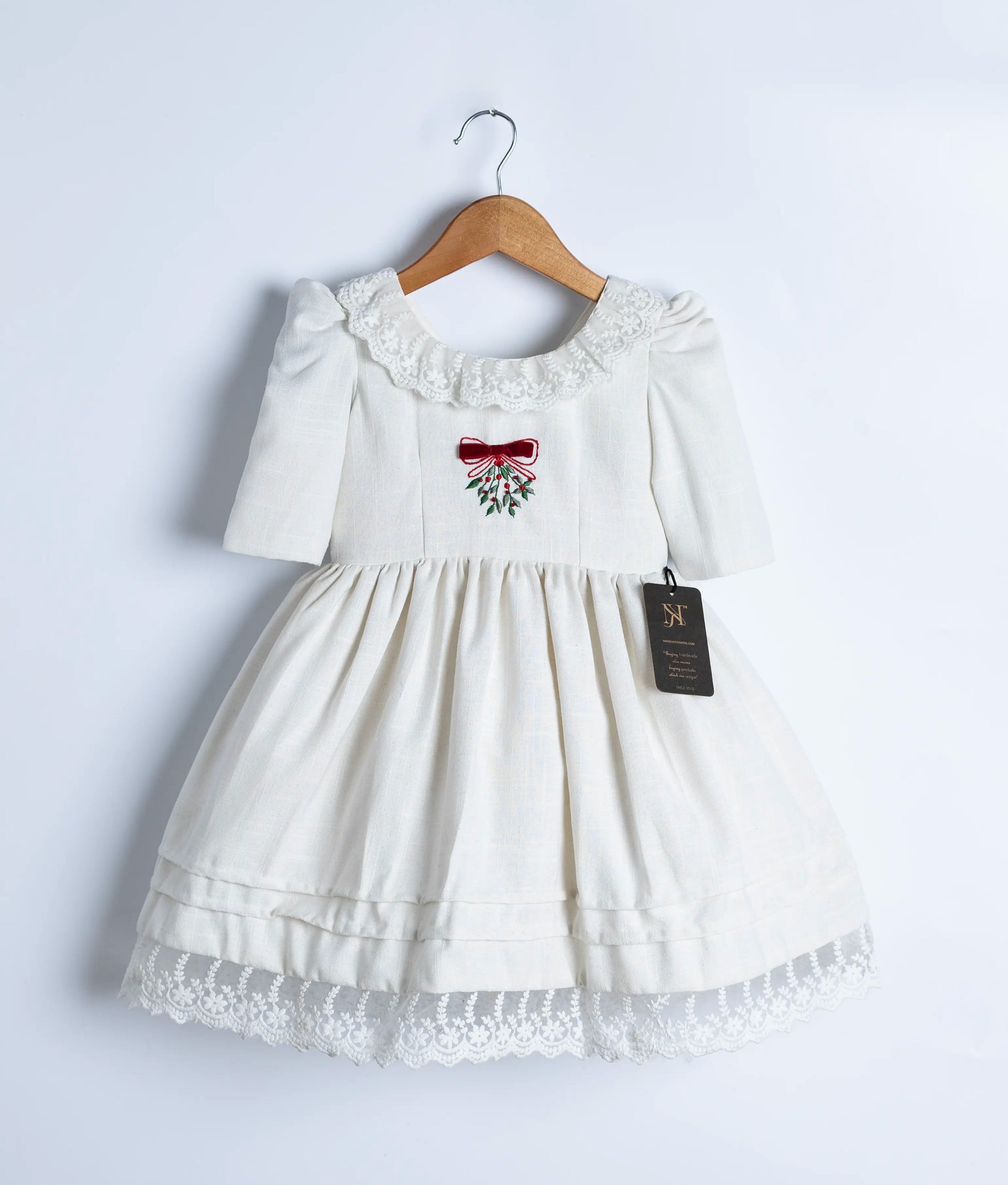 off-white linen frock showing the center embroidered design and round neckline.
