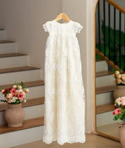 Front view of an off-white, long-length baptism gown featuring floral embroidery and beadwork on the bottom.