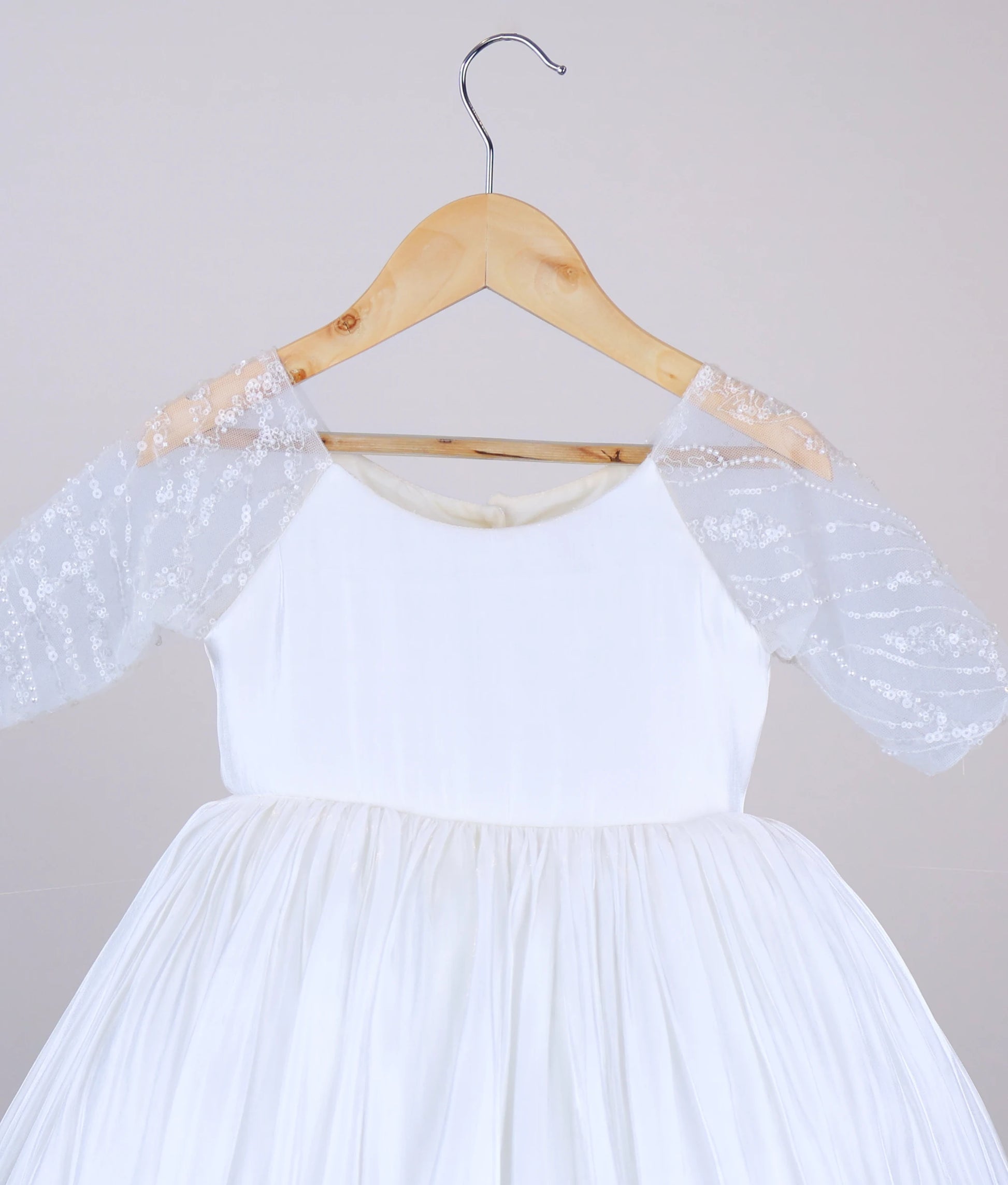 Close-up of the delicate worked-material embellishments on the sheer medium-length sleeves of the off-white lacer organza dress