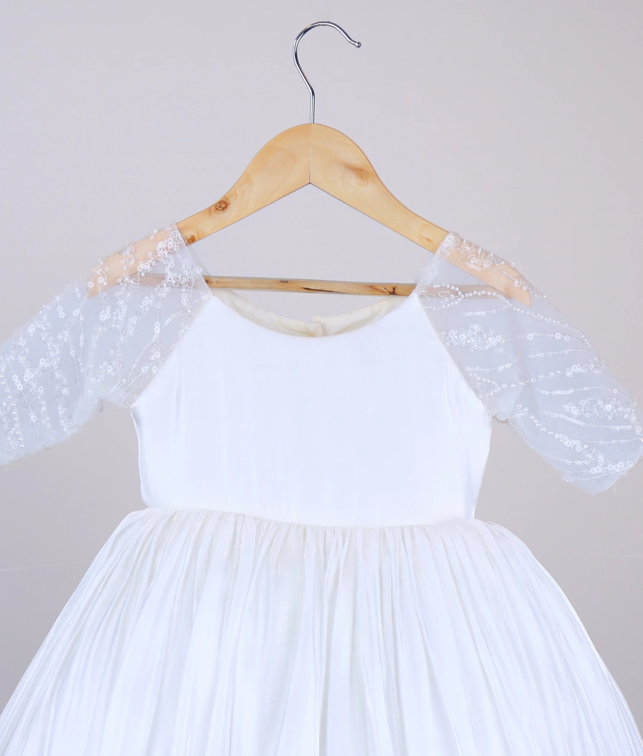 Close-up of the delicate worked-material embellishments on the sheer medium-length sleeves of the off-white lacer organza dress