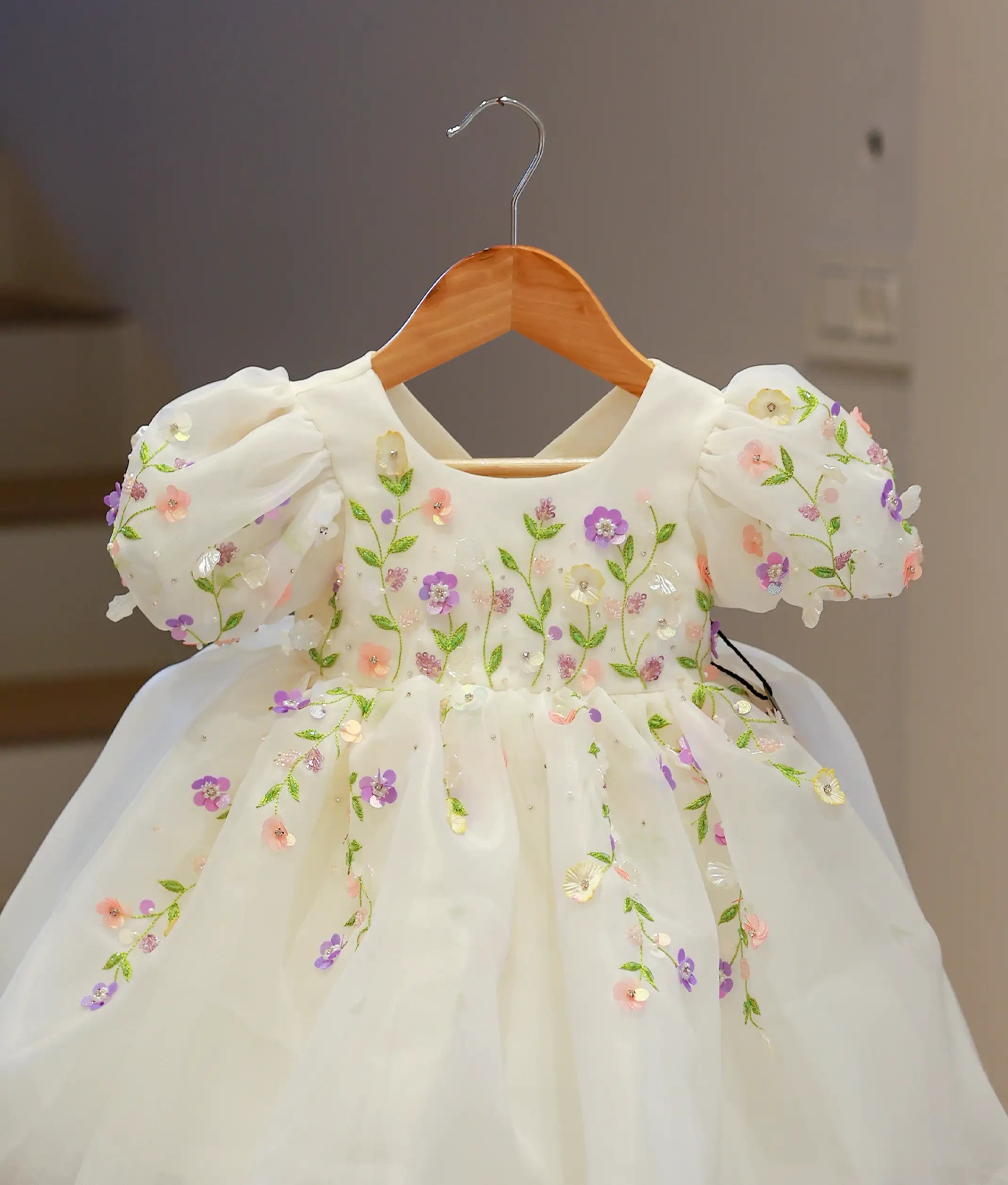 Close-up of the off-white frock highlighting the intricate lavender and peach floral handwork with shimmering sequins