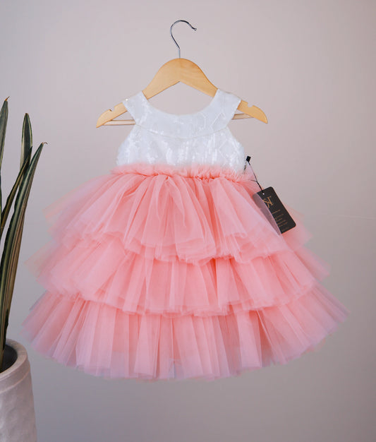 Front view of an off-white and pink tulle net birthday frock with a halter neck and tiered step flare.
