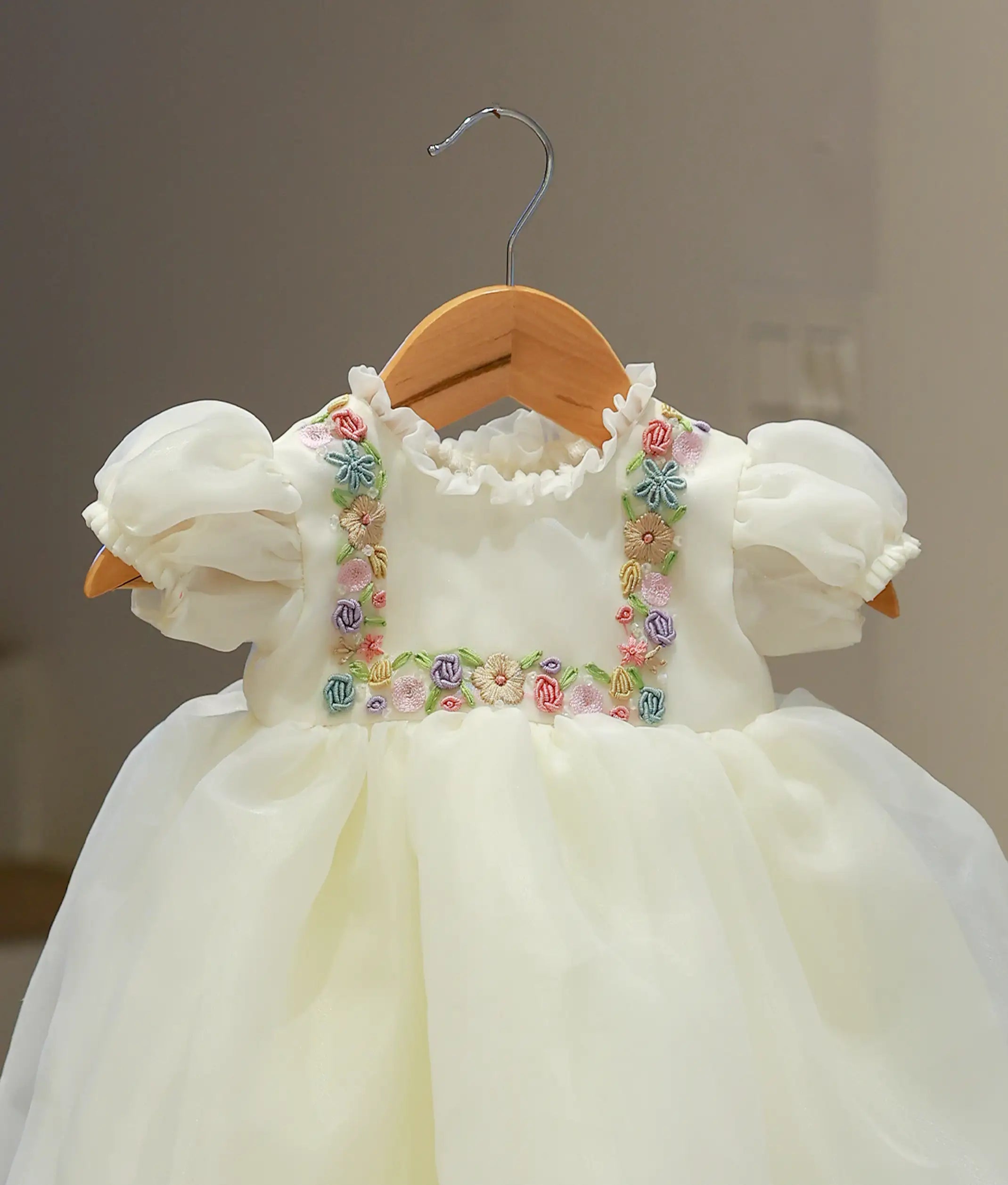 Close-up of the off-white baptism frock highlighting the intricate handworked floral motifs and the smooth finish of the plain organza fabric