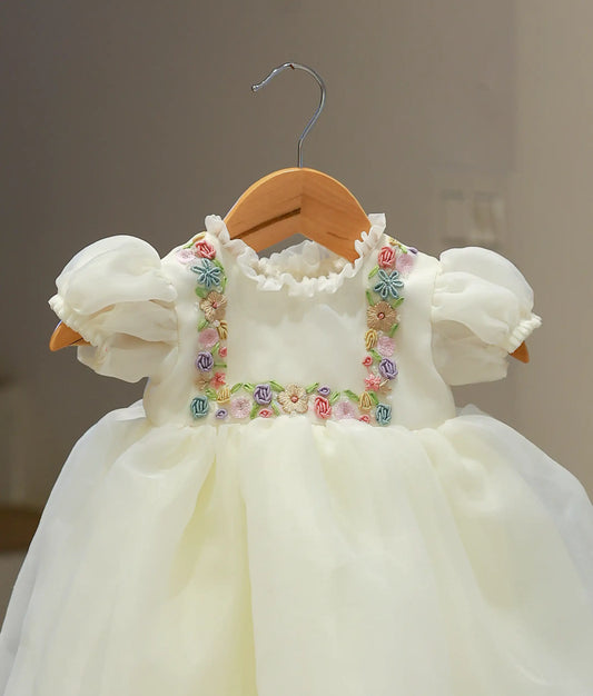 Close-up of the off-white baptism frock highlighting the intricate handworked floral motifs and the smooth finish of the plain organza fabric