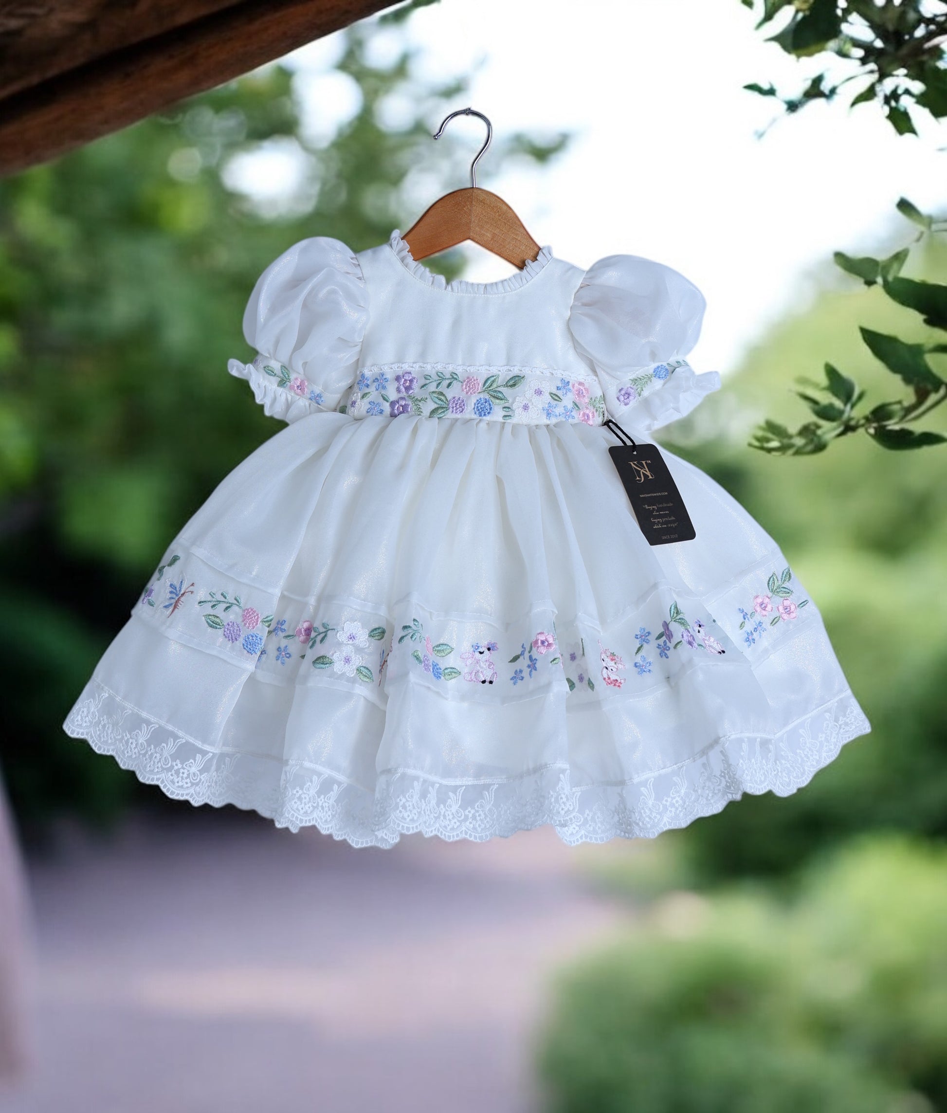 Front view of off-white shimmer organza birthday frock for baby girls featuring cartoon theme embroidery and puff sleeves