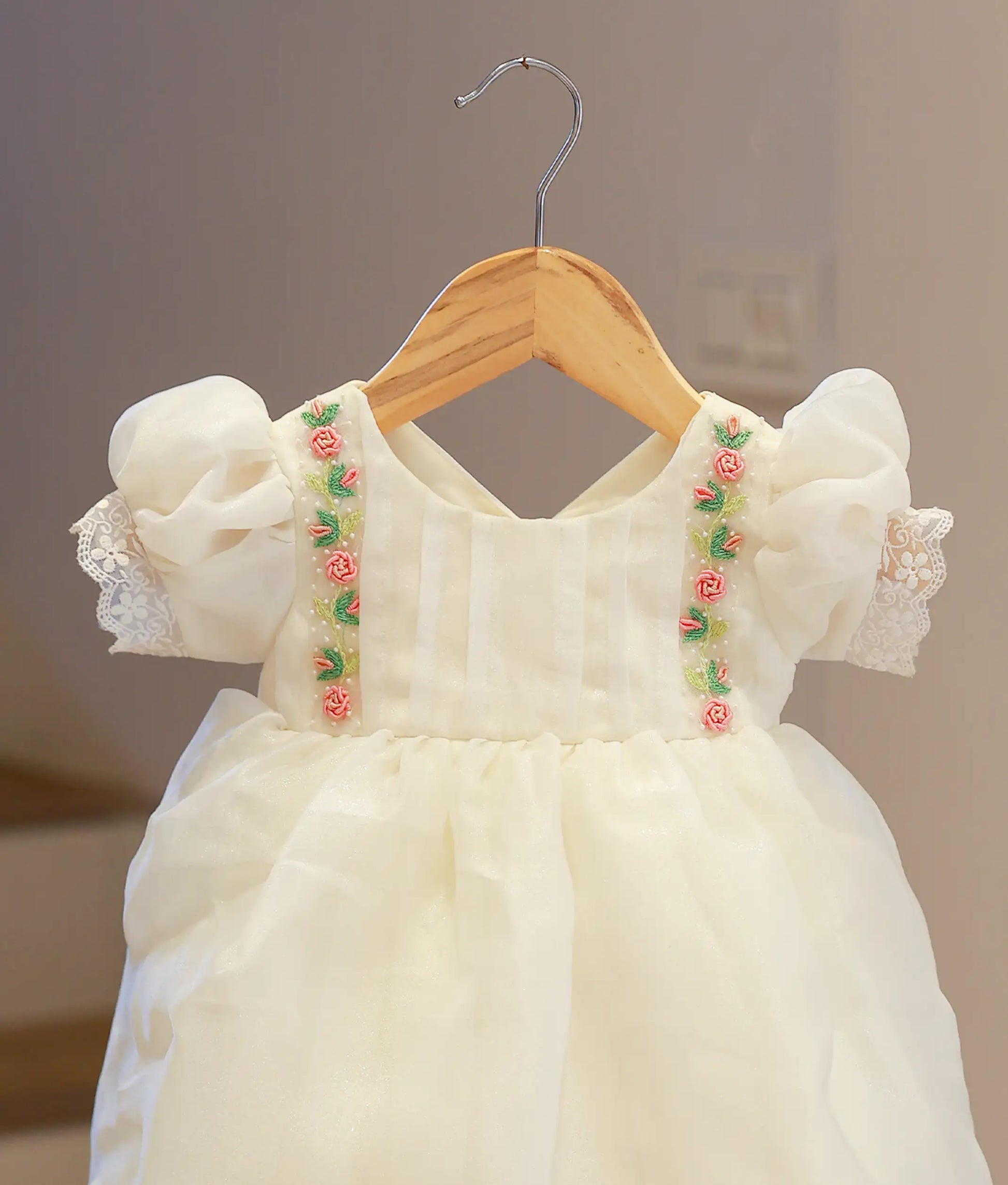 Close-up of the off-white baptism frock highlighting the shimmering organza fabric and the intricate hand-worked sequin and thread details.