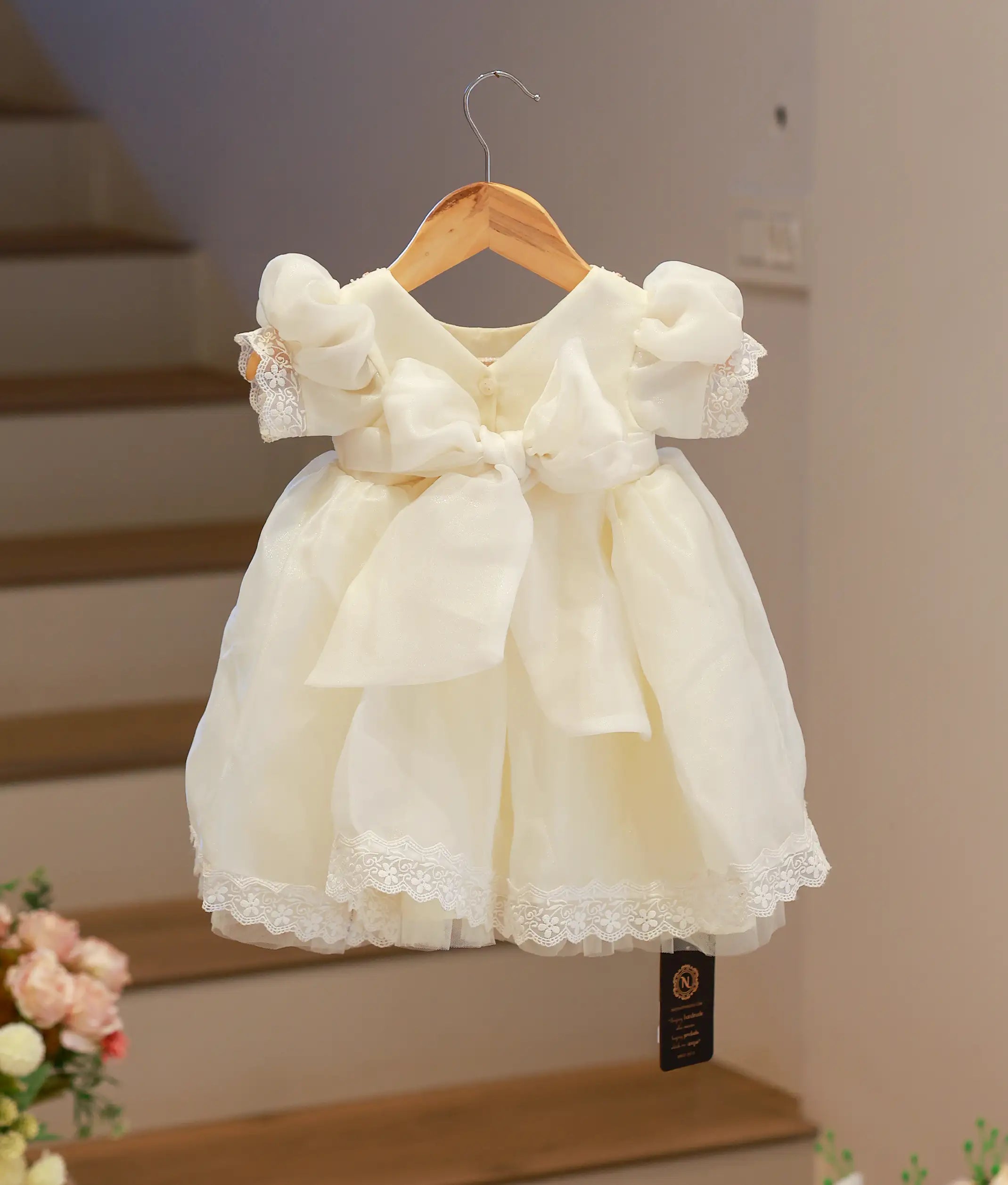 Back view of the shimmering off-white organza baptism frock showing the elegant fastening and sheer fabric finish