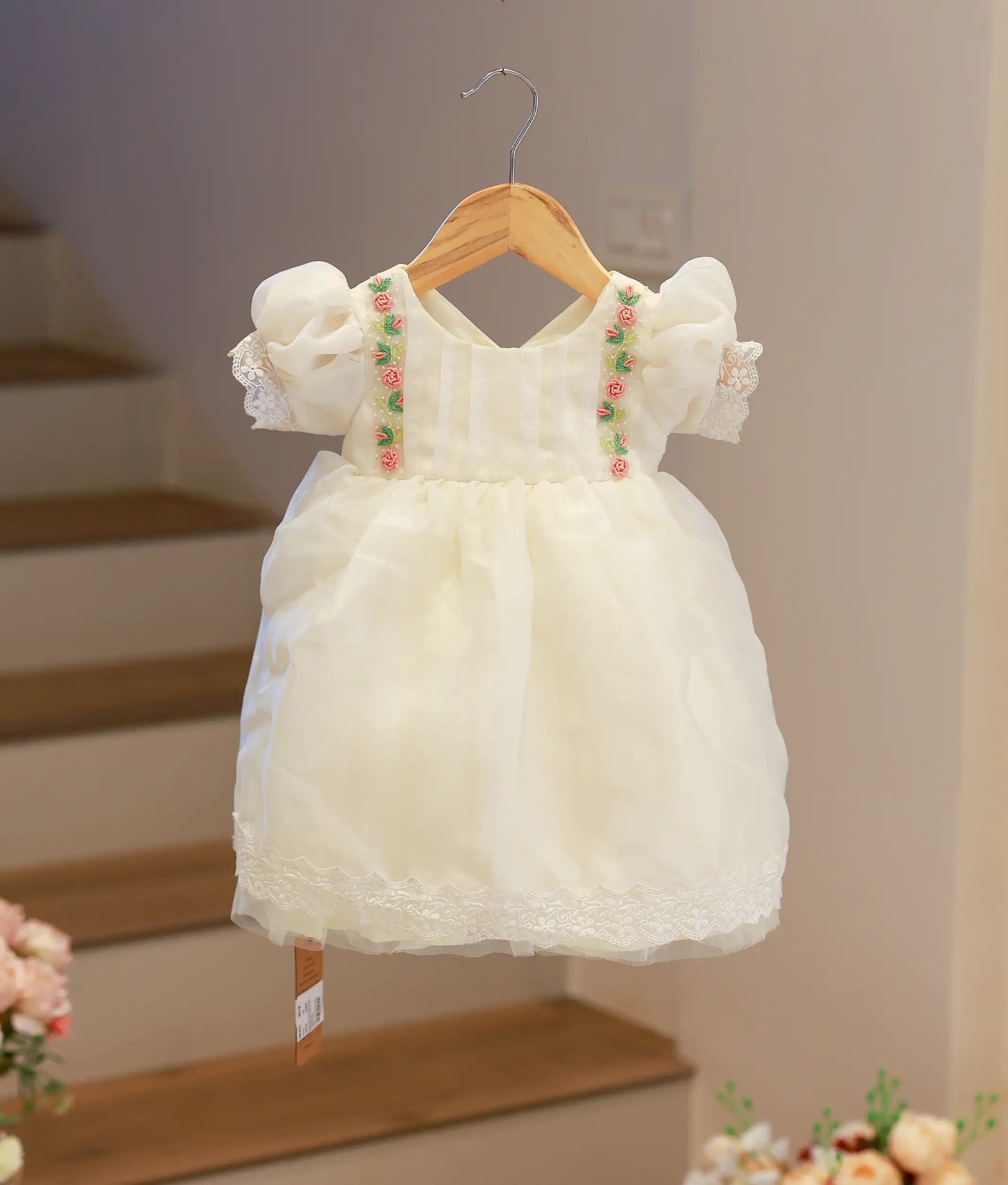 Front view of a baby girl baptism frock in off-white shimmer organza featuring delicate hand-worked floral embroidery
