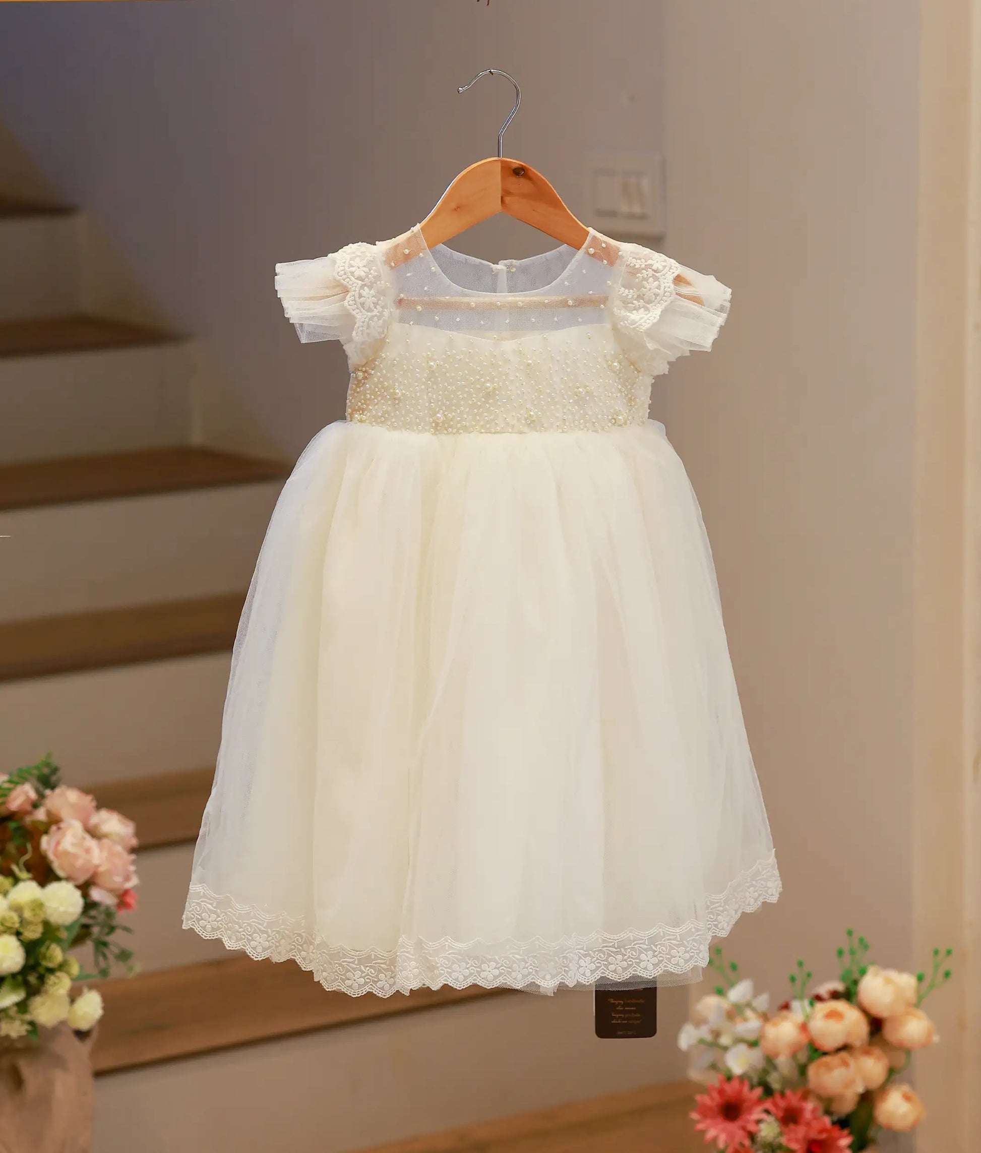 Full front view of an off-white baby girl baptism frock featuring a hand-embroidered bodice and a soft tulle net skirt.