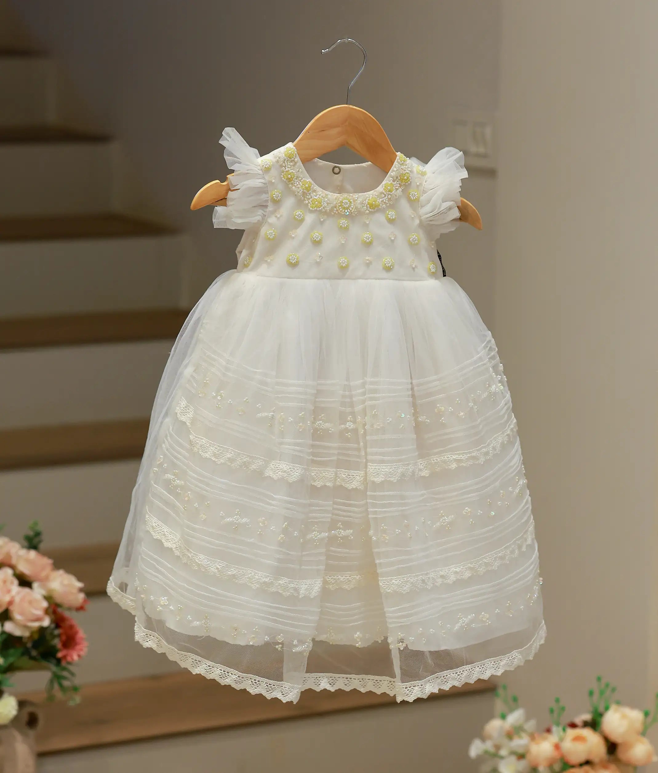 Full front view of an off-white baptism gown for baby girls featuring a hand-worked bodice and a long, flowing tulle net skirt.