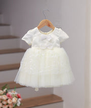 Front view of an elegant off-white bridal satin frock for baby girls with hand embroidery and a decorative bow
