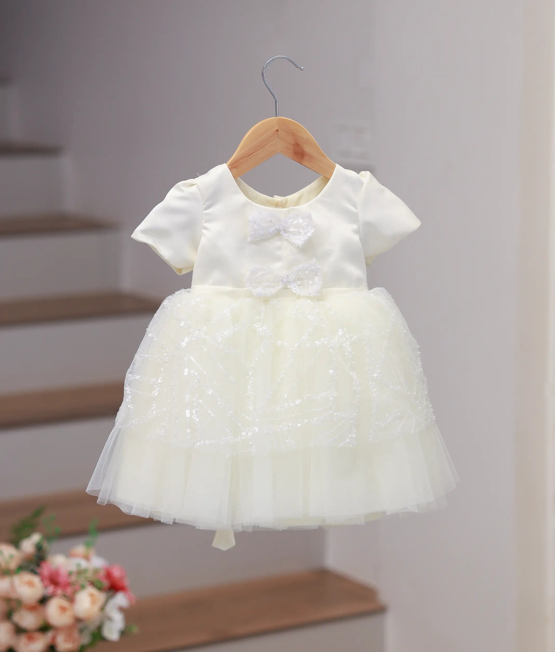 Front view of an elegant off-white bridal satin frock for baby girls with hand embroidery and a decorative bow
