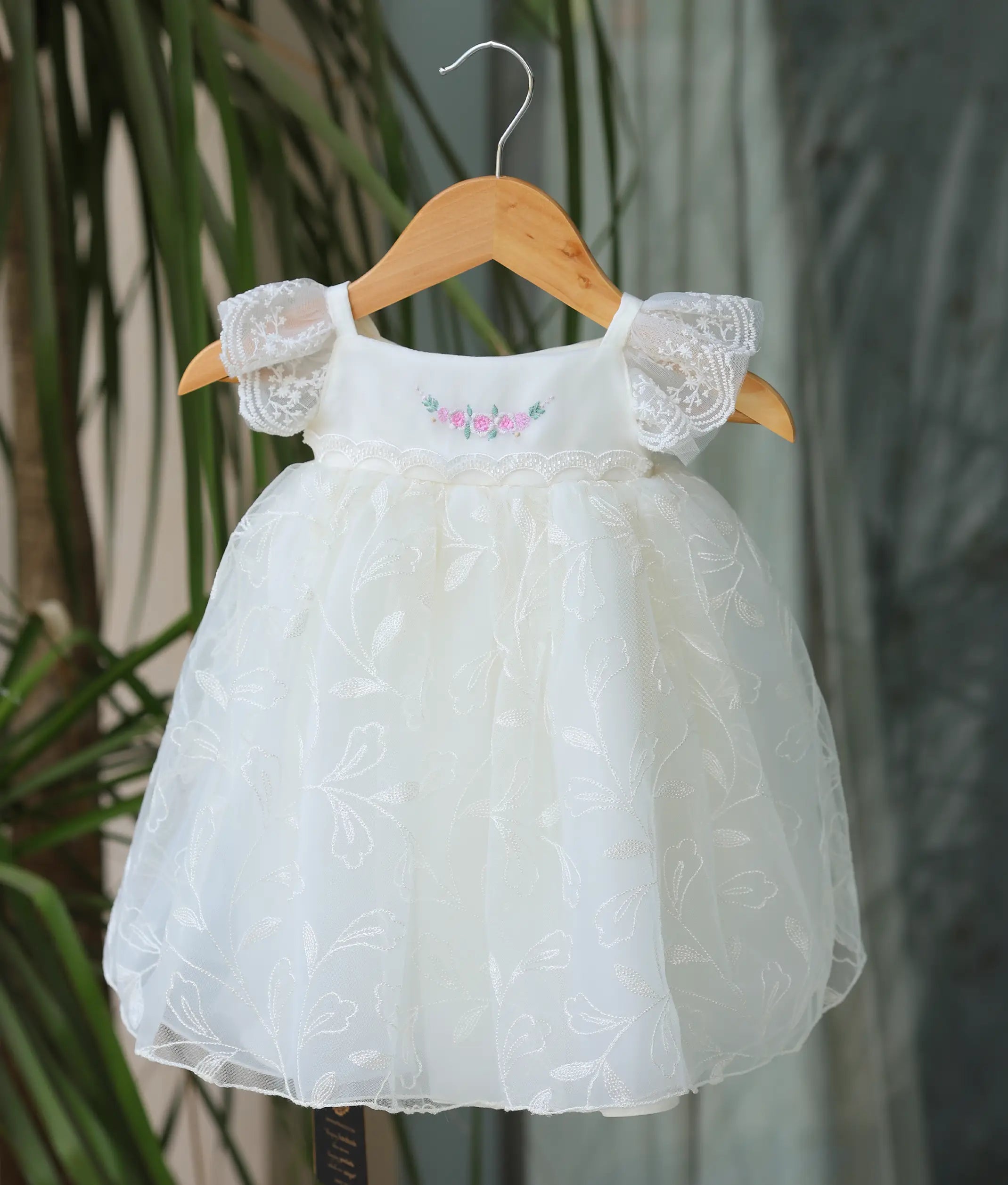 Front view of an off-white full-length baptism gown for girls with floral work material and lace sleeves.