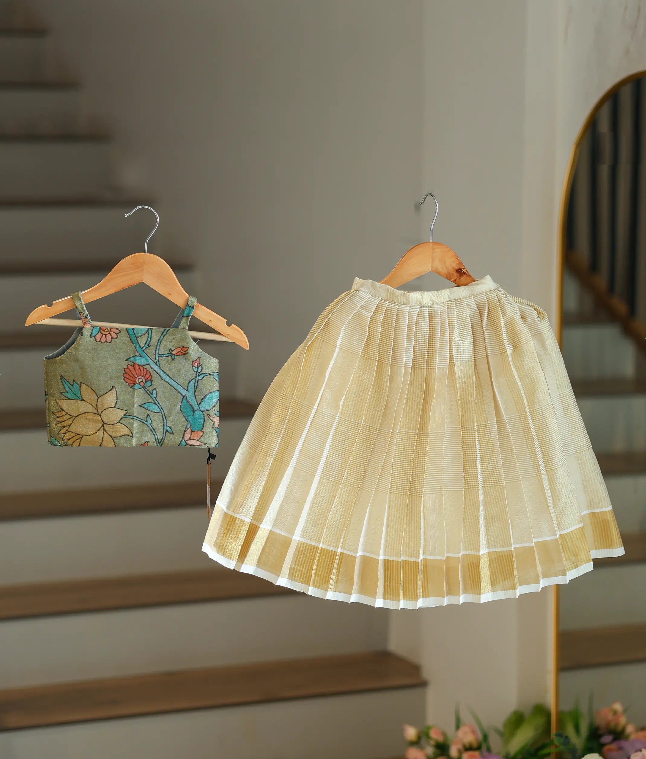 Front view of a girl's olive green skirt and top set with a floral top and kasavu skirt.