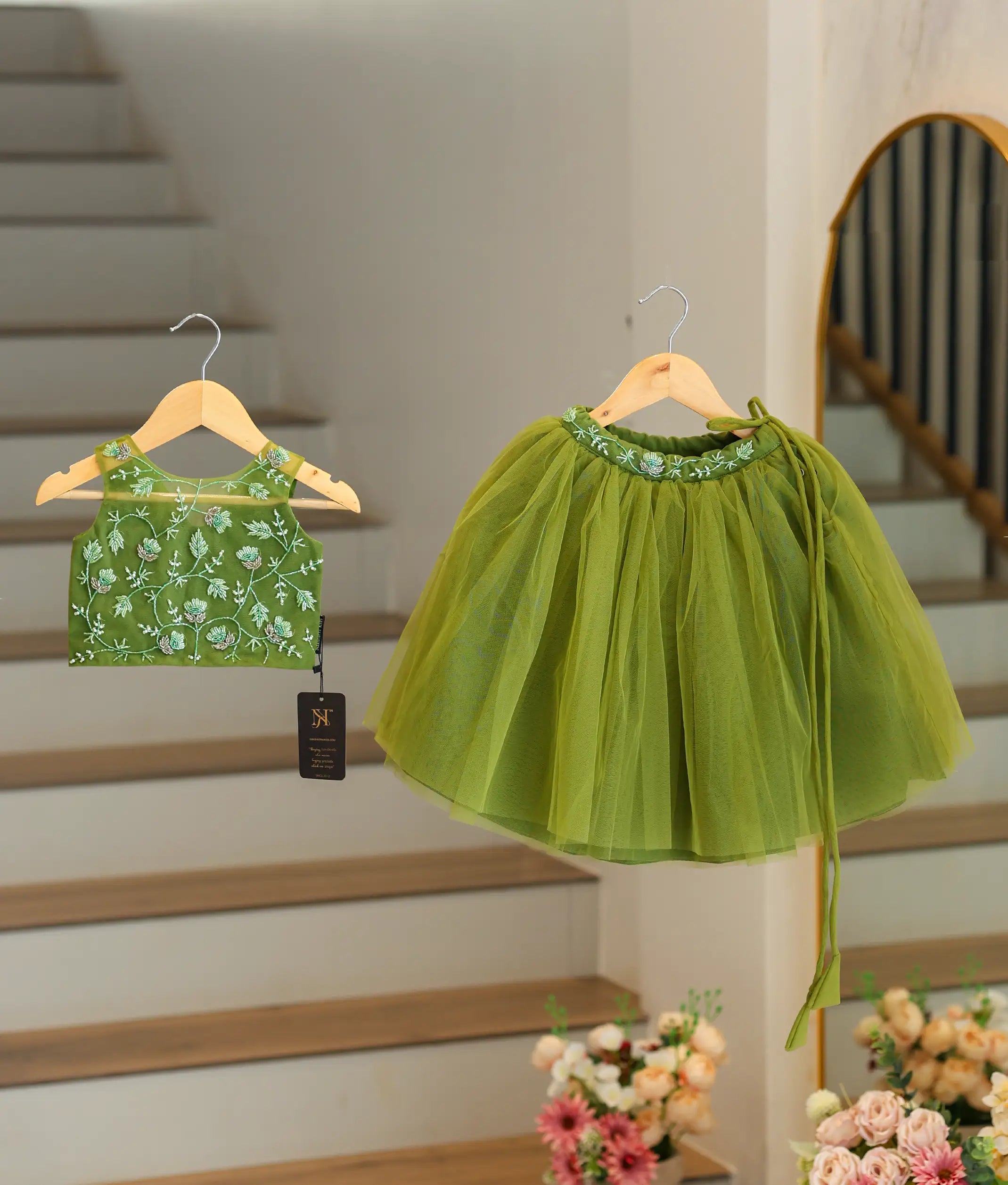 Front view of an olive green baby girl outfit with white floral hand-embroidery and a long net skirt