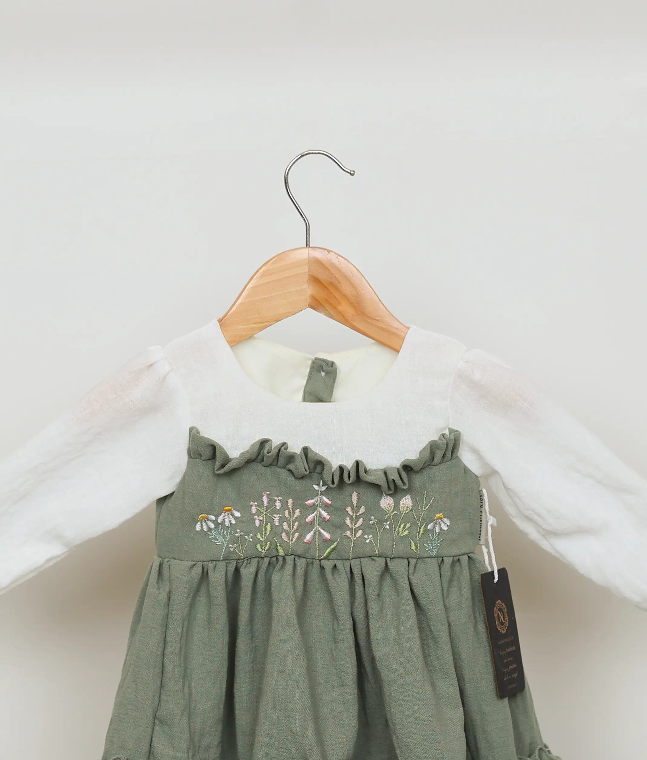 Close view of an green linen floral embroidery christmas frock for baby girls.
