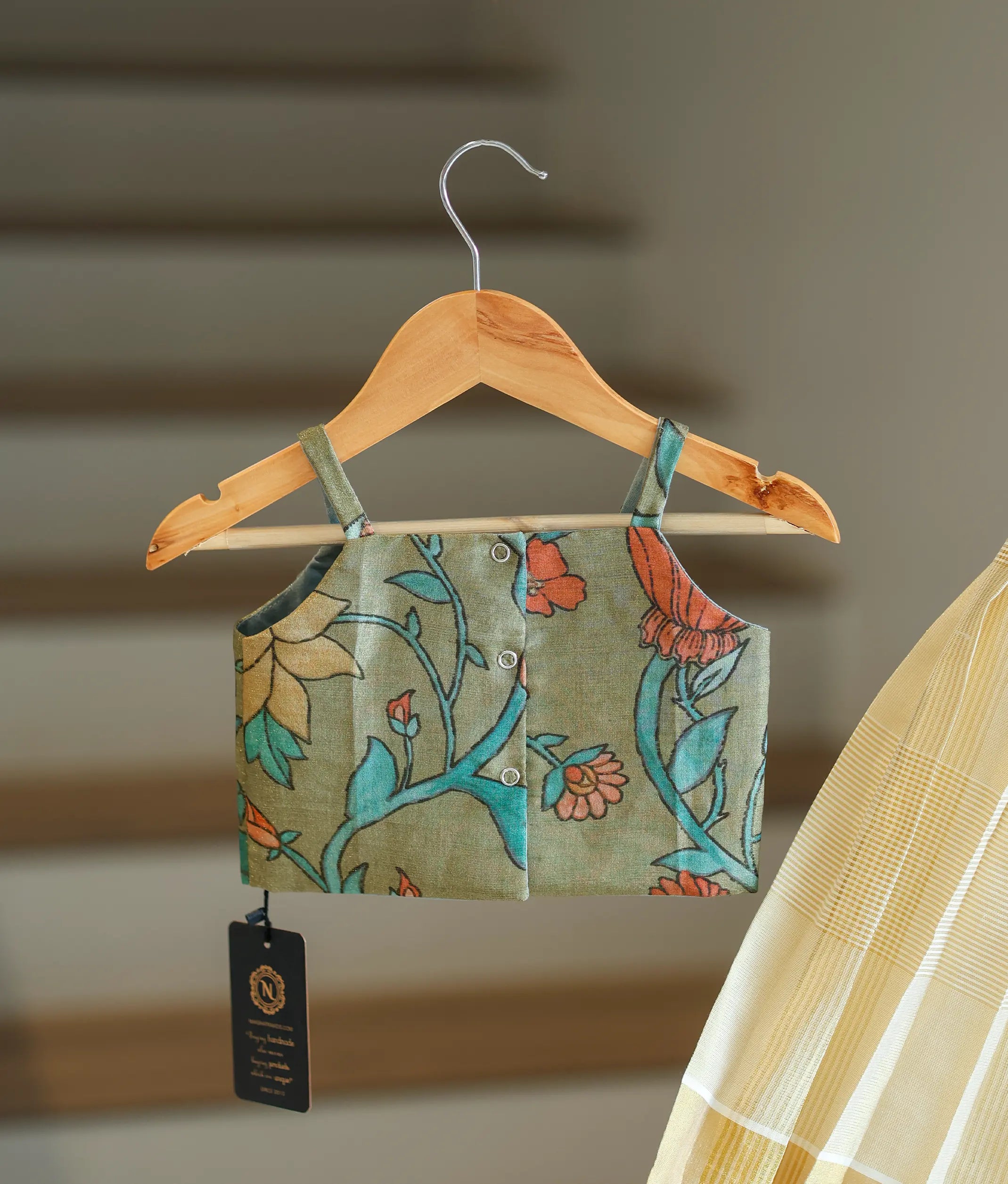 Back view of the olive green floral-patterned top showing the neat button closures and strap design.