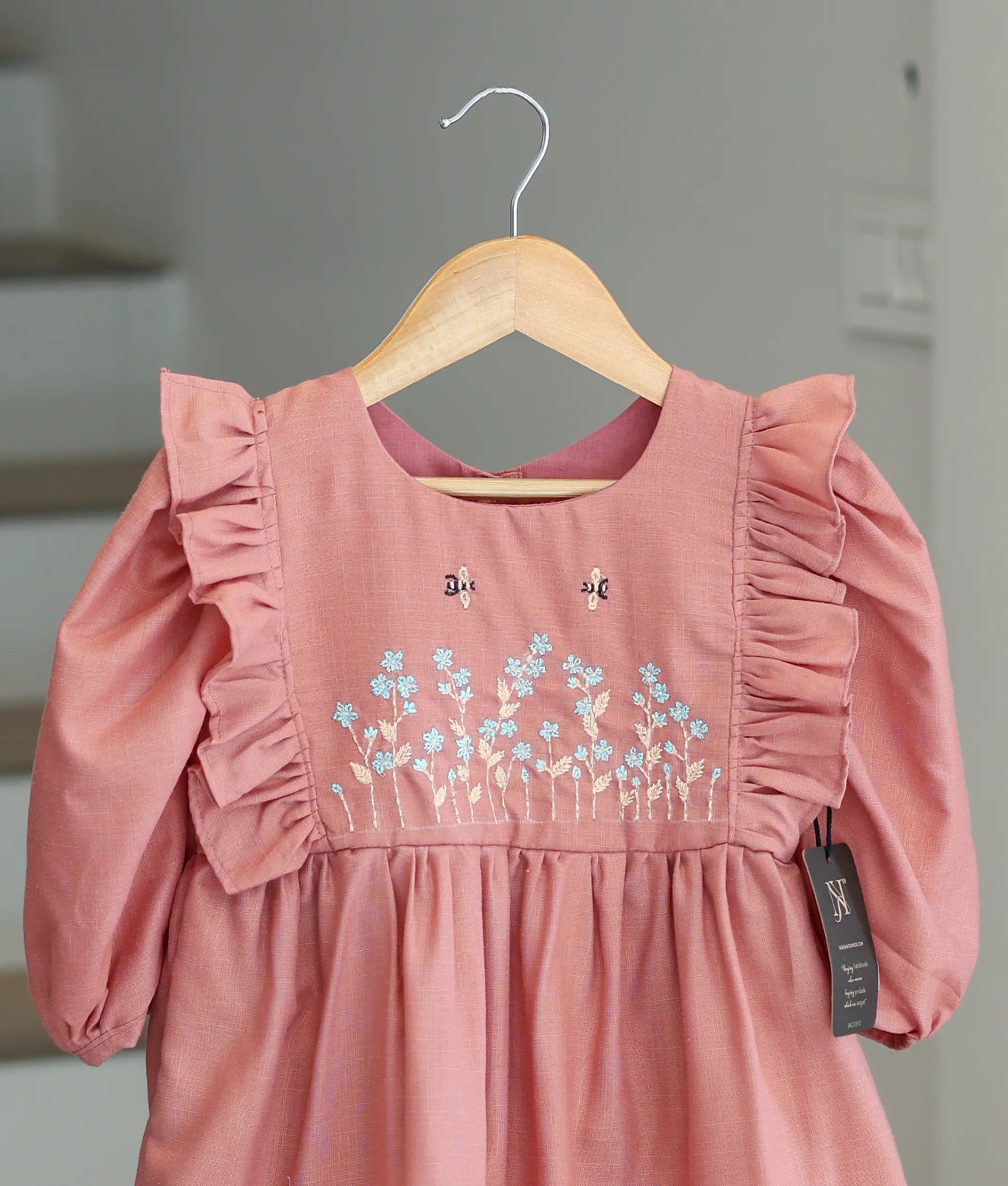 Close-up of the cotton dress showing the detailed handmade floral embroidery and pearl accents