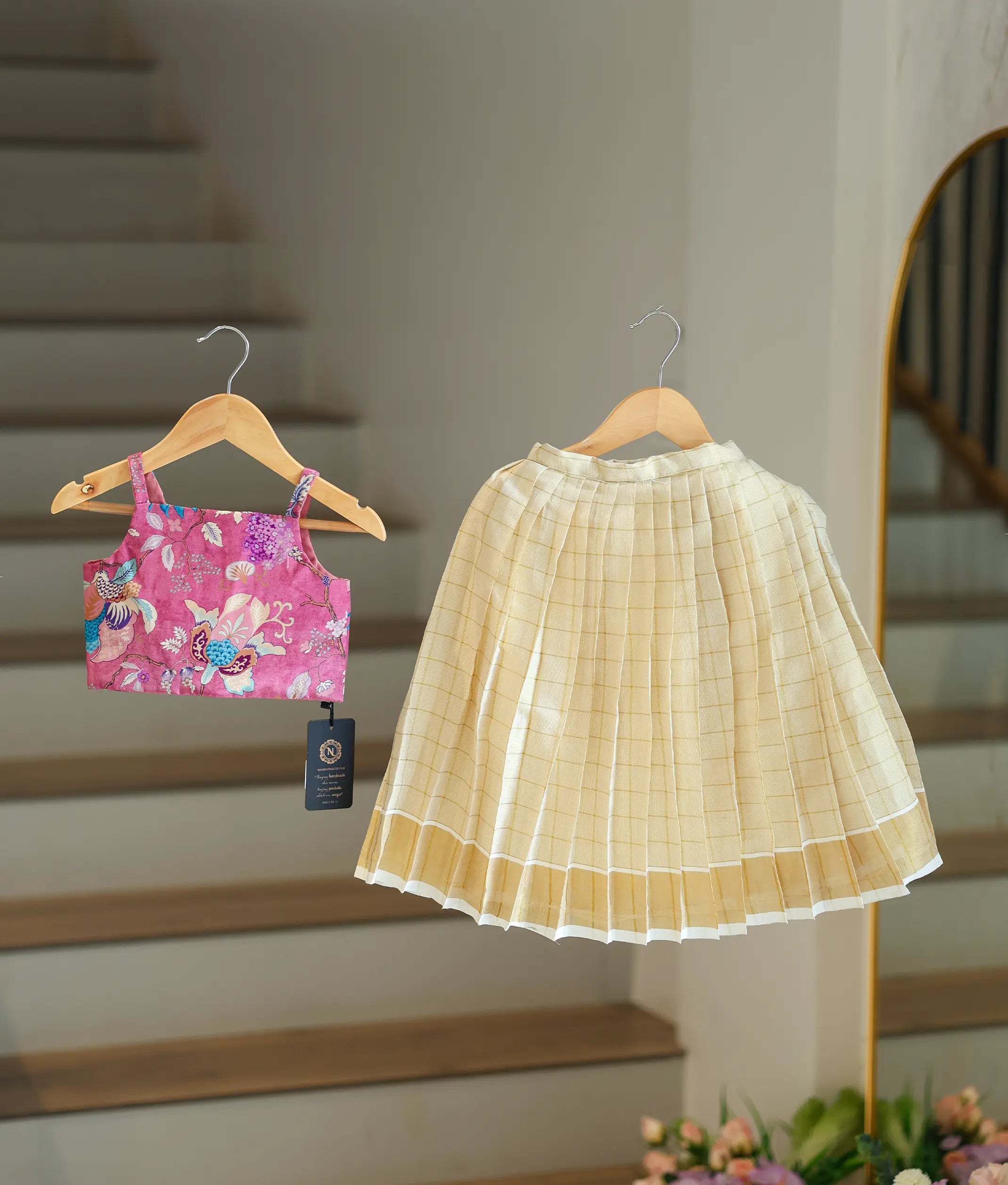 Front view of a girl's onion-pink skirt and top set with a floral top and kasavu skirt.