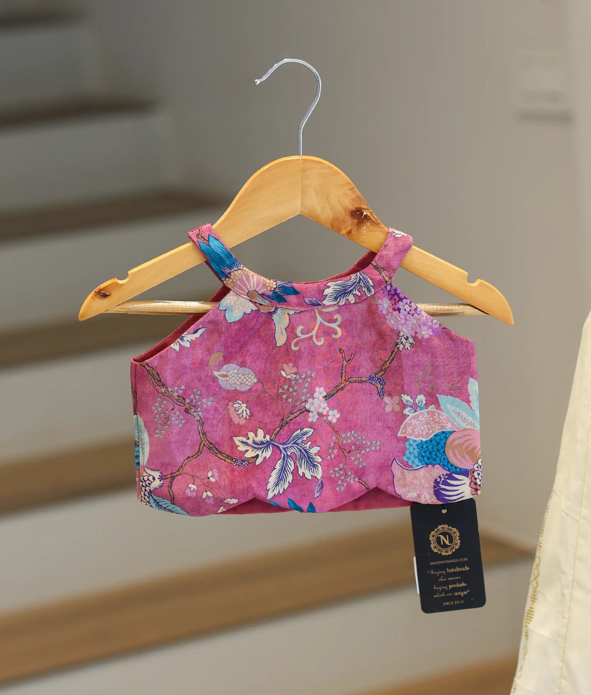 Close-up showing the colorful floral pattern and halter neck on the pink top.