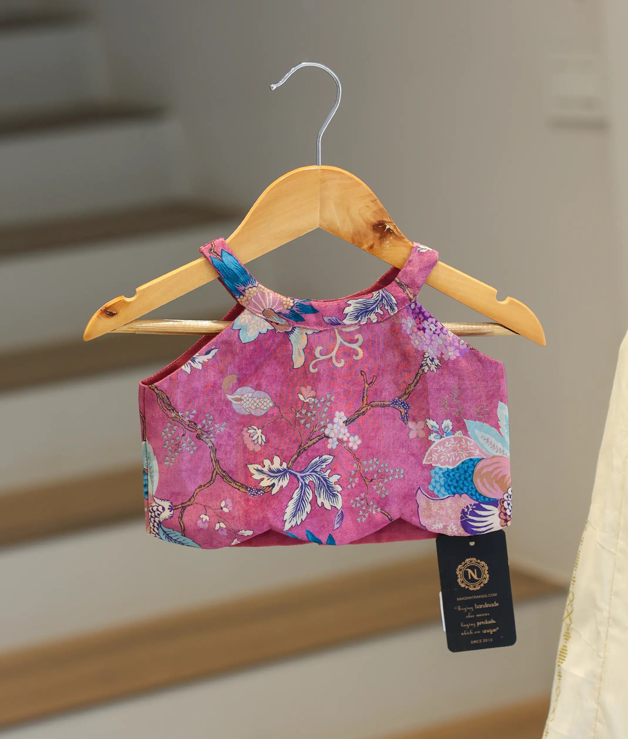 Close-up showing the colorful floral pattern and halter neck on the pink top.