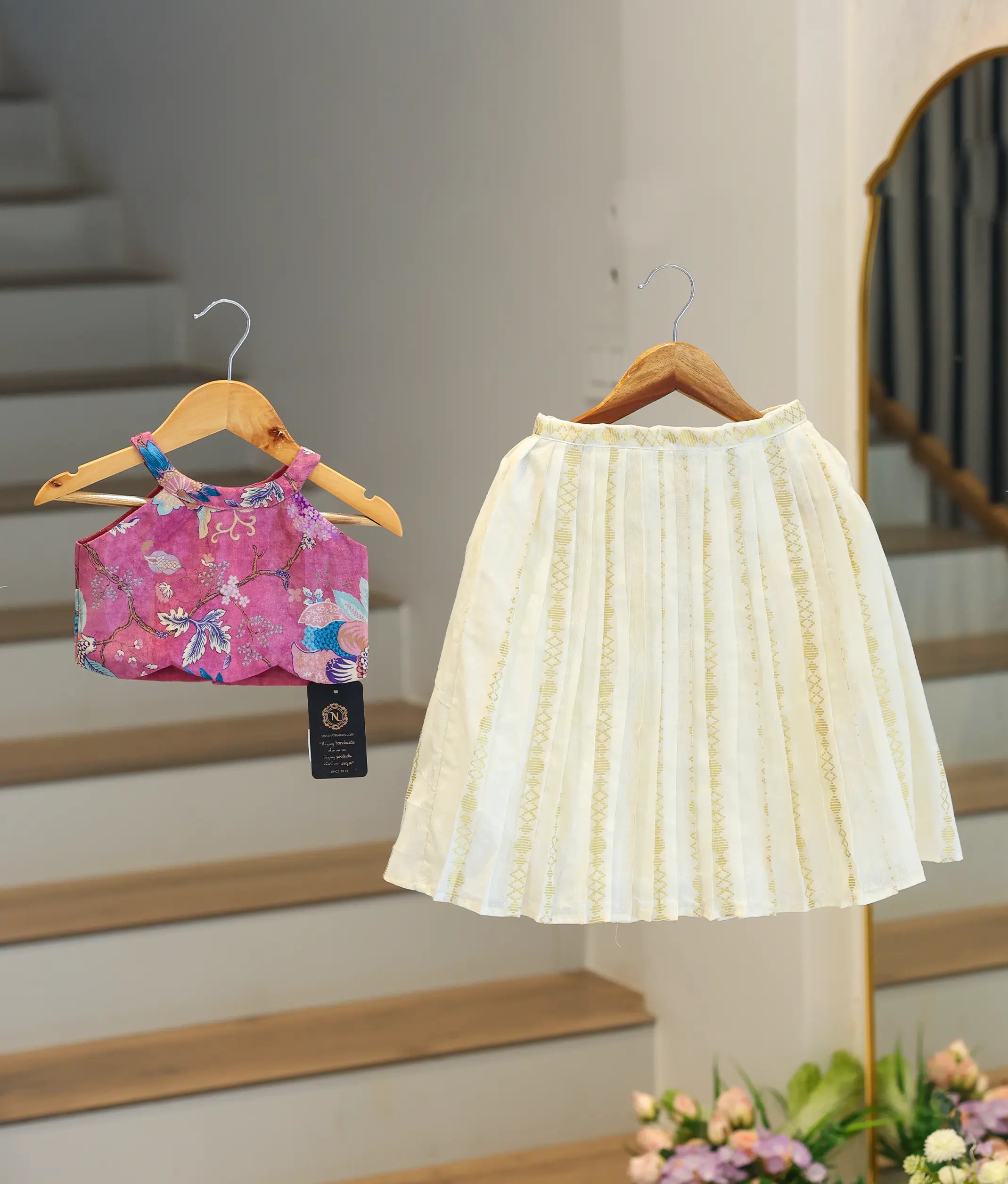 Front view of a girl's onion-pink skirt and top set with a floral top and kasavu skirt.