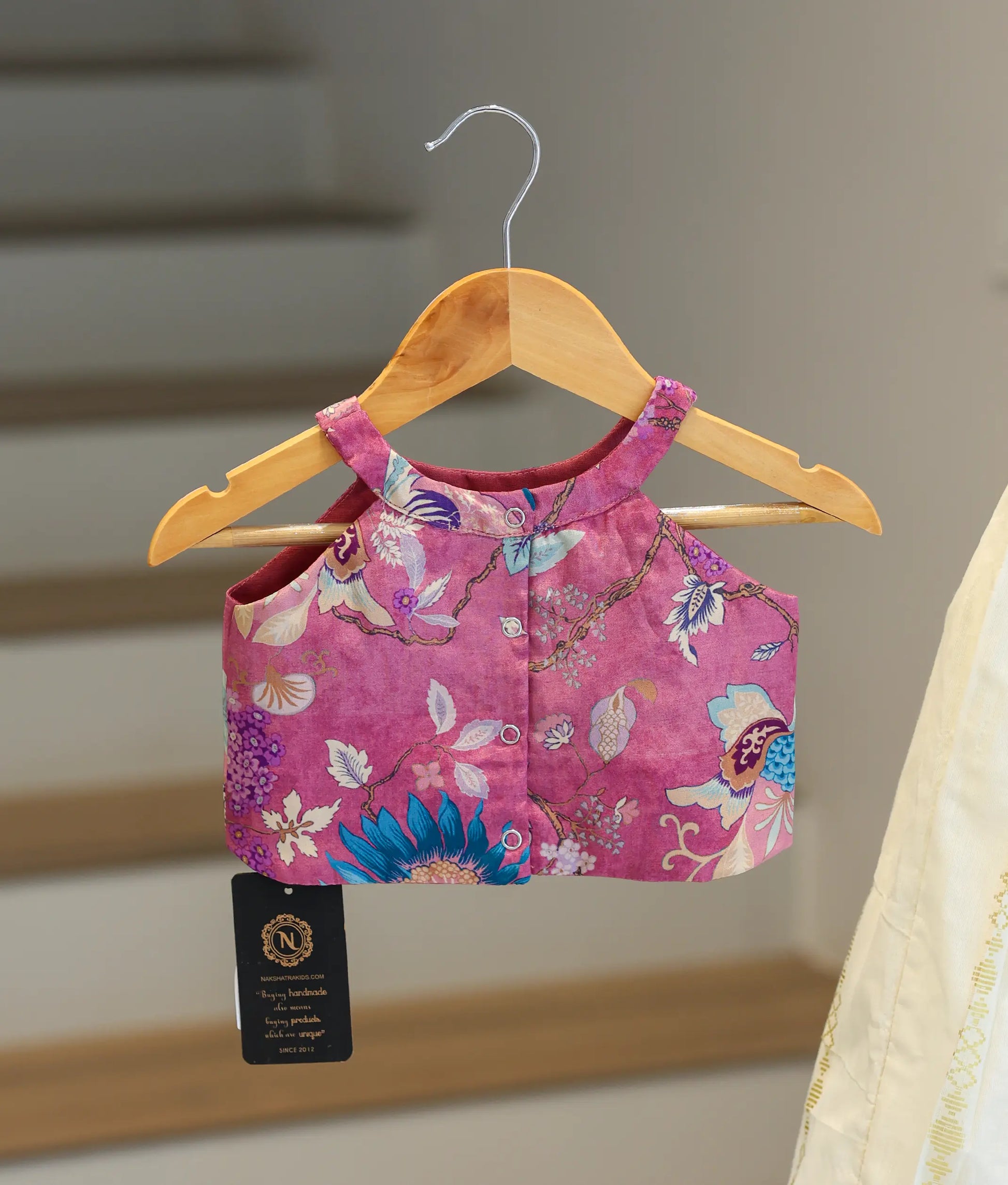 Back view of the pink floral-patterned top showing the neat button closures and halter neck design.