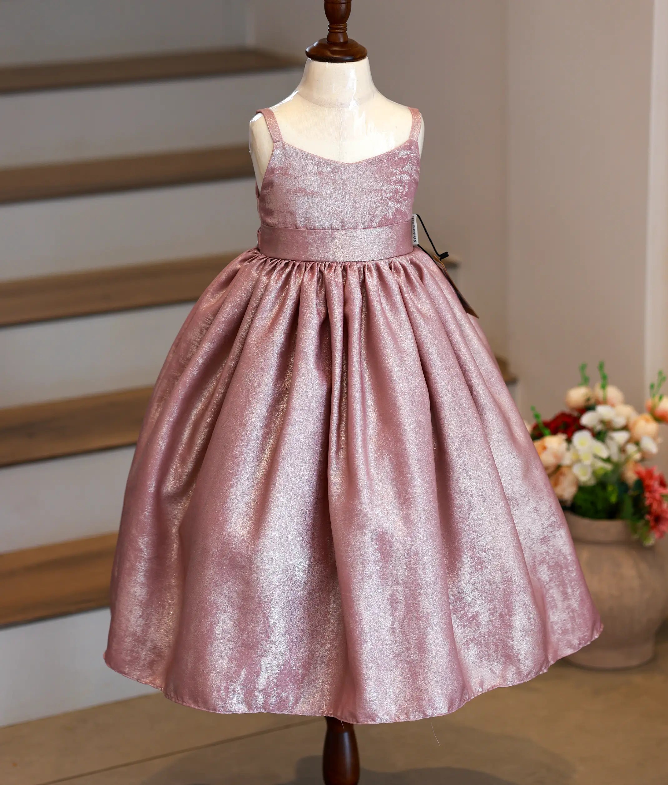 Front view of an onion pink milan foil birthday gown for baby girls featuring thin shoulder straps, square-neckline, and a pleated flared skirt