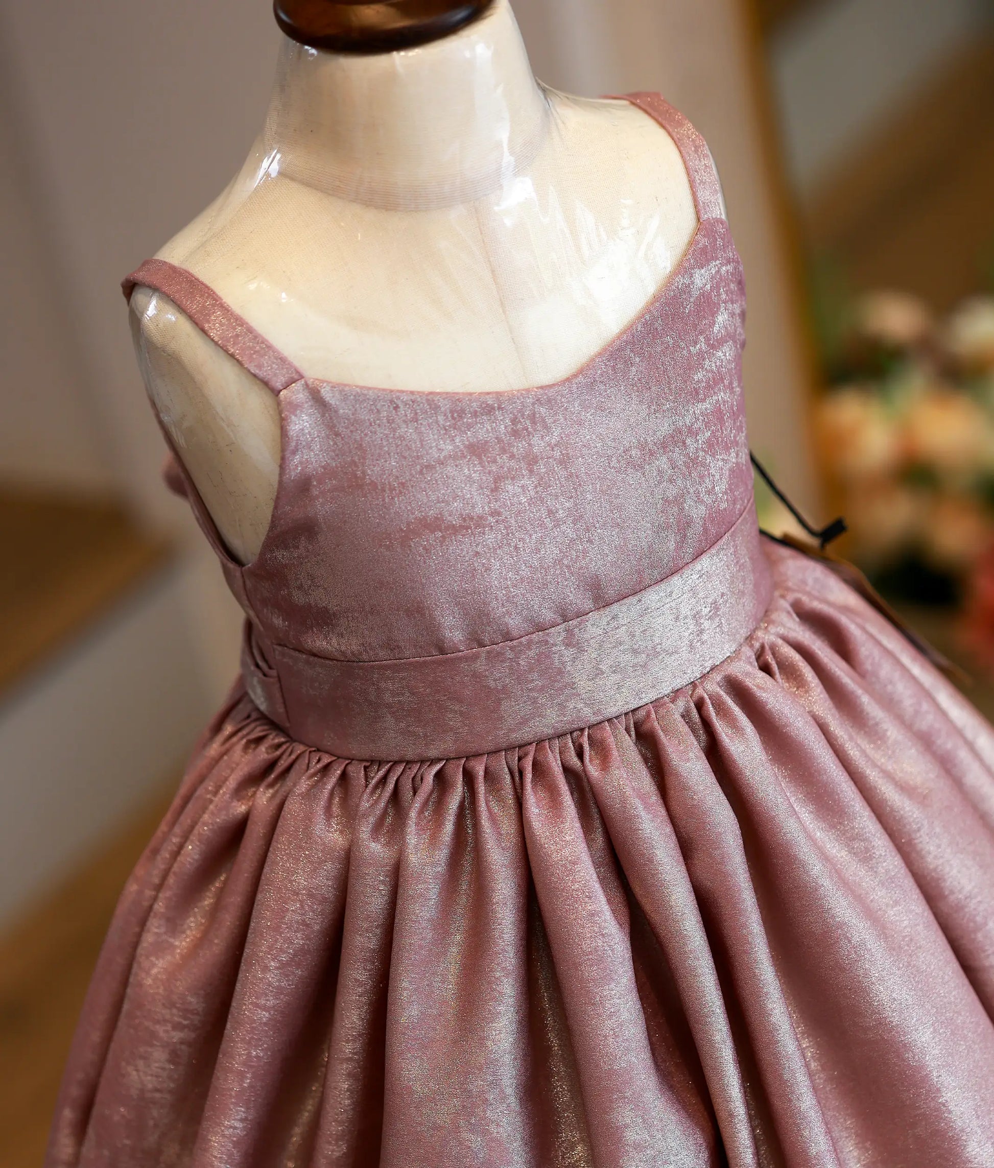 Close-up of the shimmering onion pink milan foil fabric and the neatly attached waistband detailing on the birthday gown