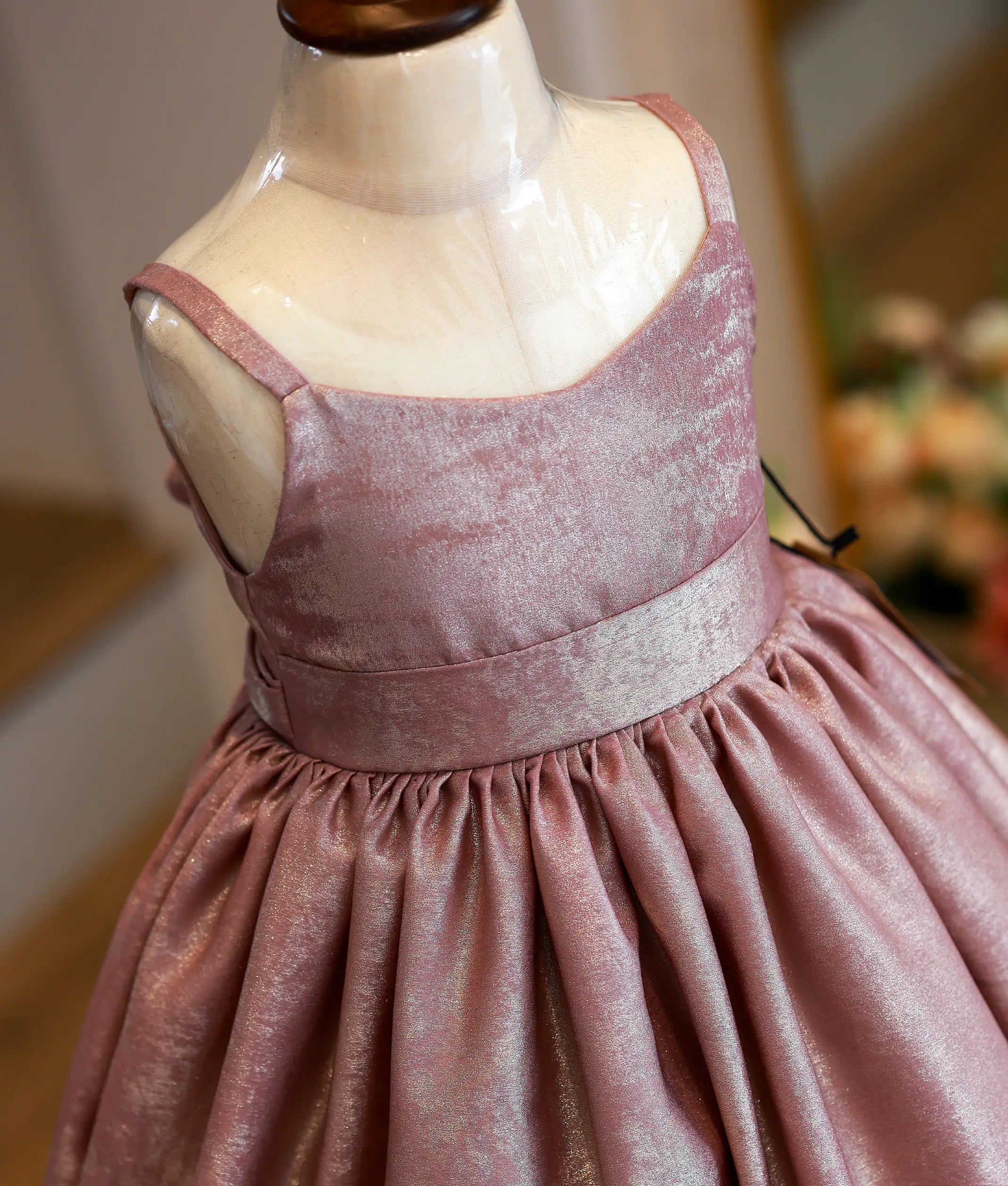 Close-up of the shimmering onion pink milan foil fabric and the neatly attached waistband detailing on the birthday gown