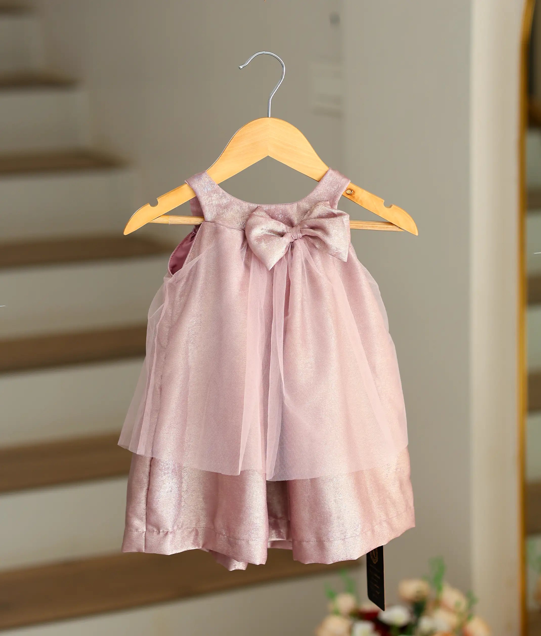 Front view of a onion pink organza birthday frock with a bown for baby girls with floral sequin designs
