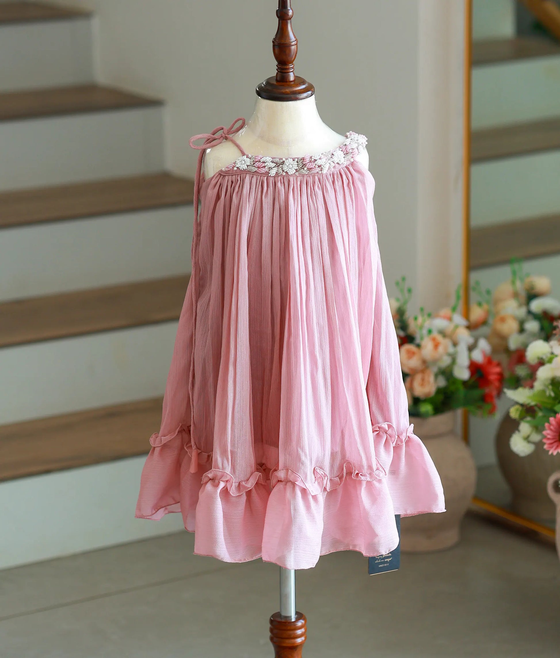 Front view of an onion pink shimmer georgette knee-length frock with pleated detailing.