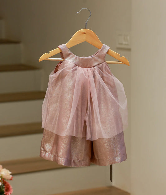 Front view of a knee-length onion pink shimmering Milan foil frock with a halter neck and tulle drape.