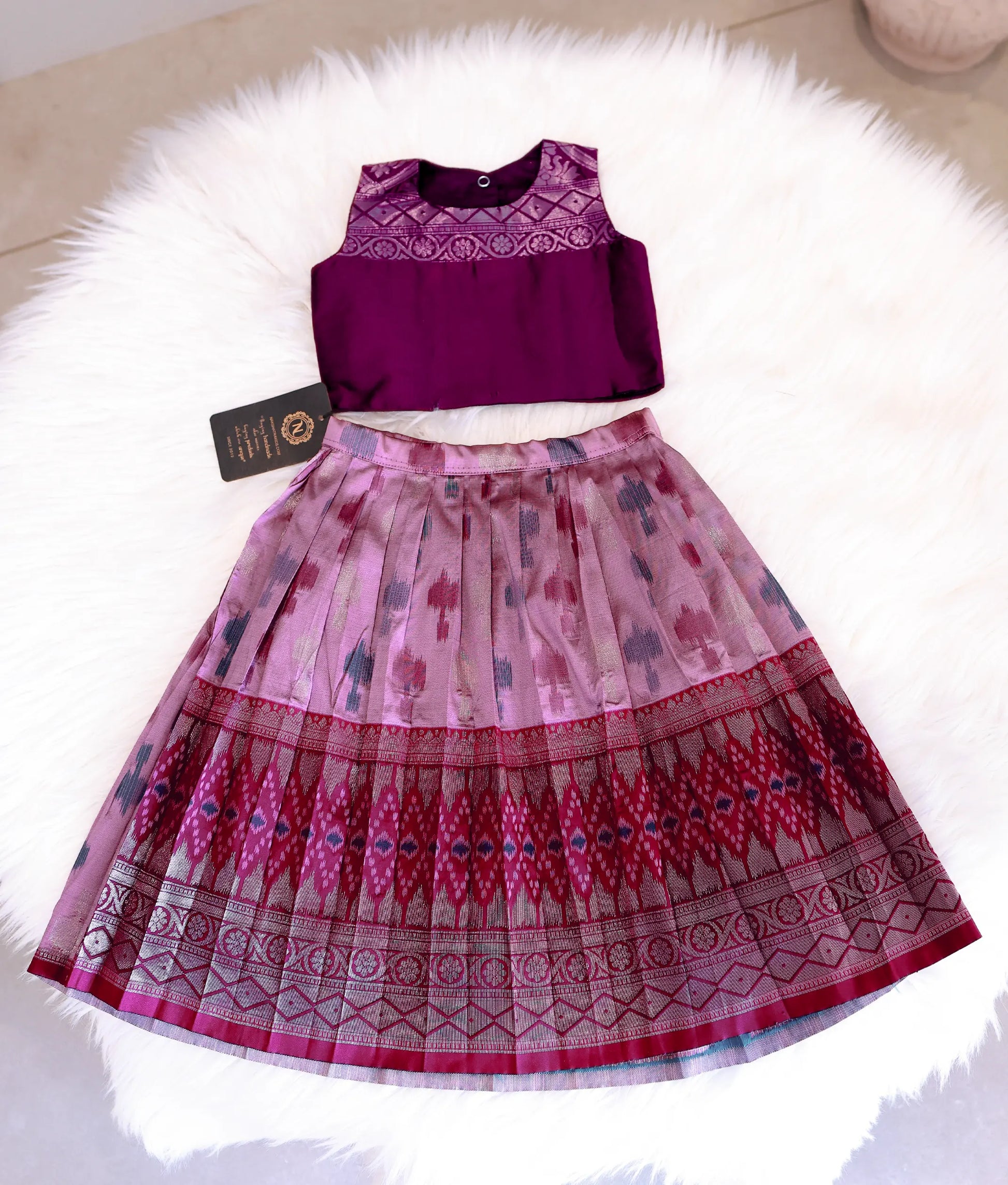 Front view of an onion pink and wine Kanchipuram silk skirt and top set for girls.