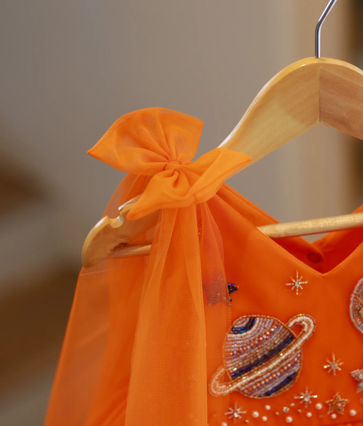 Close-up view of orange tulle net shoulder strap tied in a delicate bow drape.