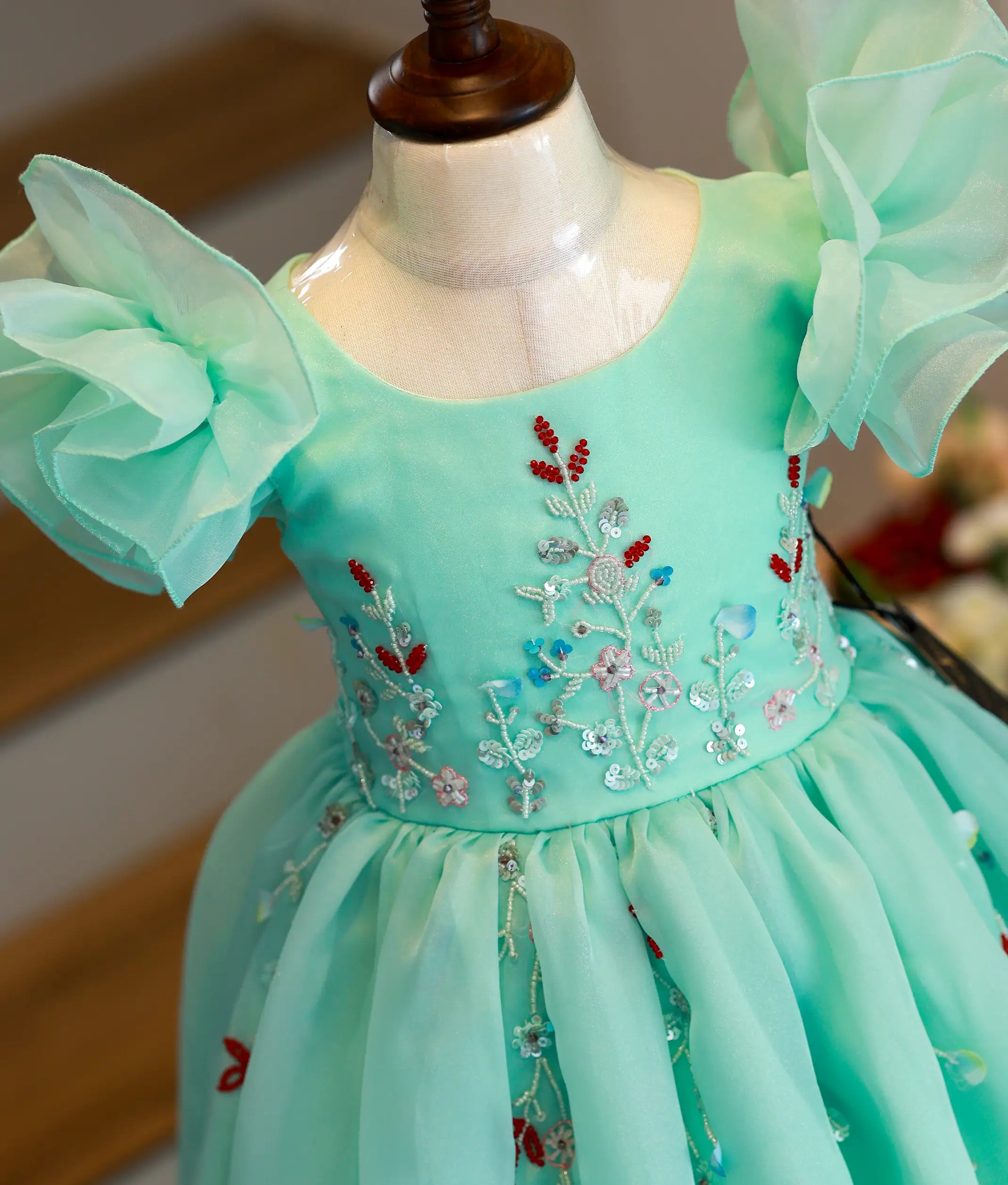 Close-up of the intricate pink floral handwork, beads, and sequins on the sea green organza birthday gown bodice
