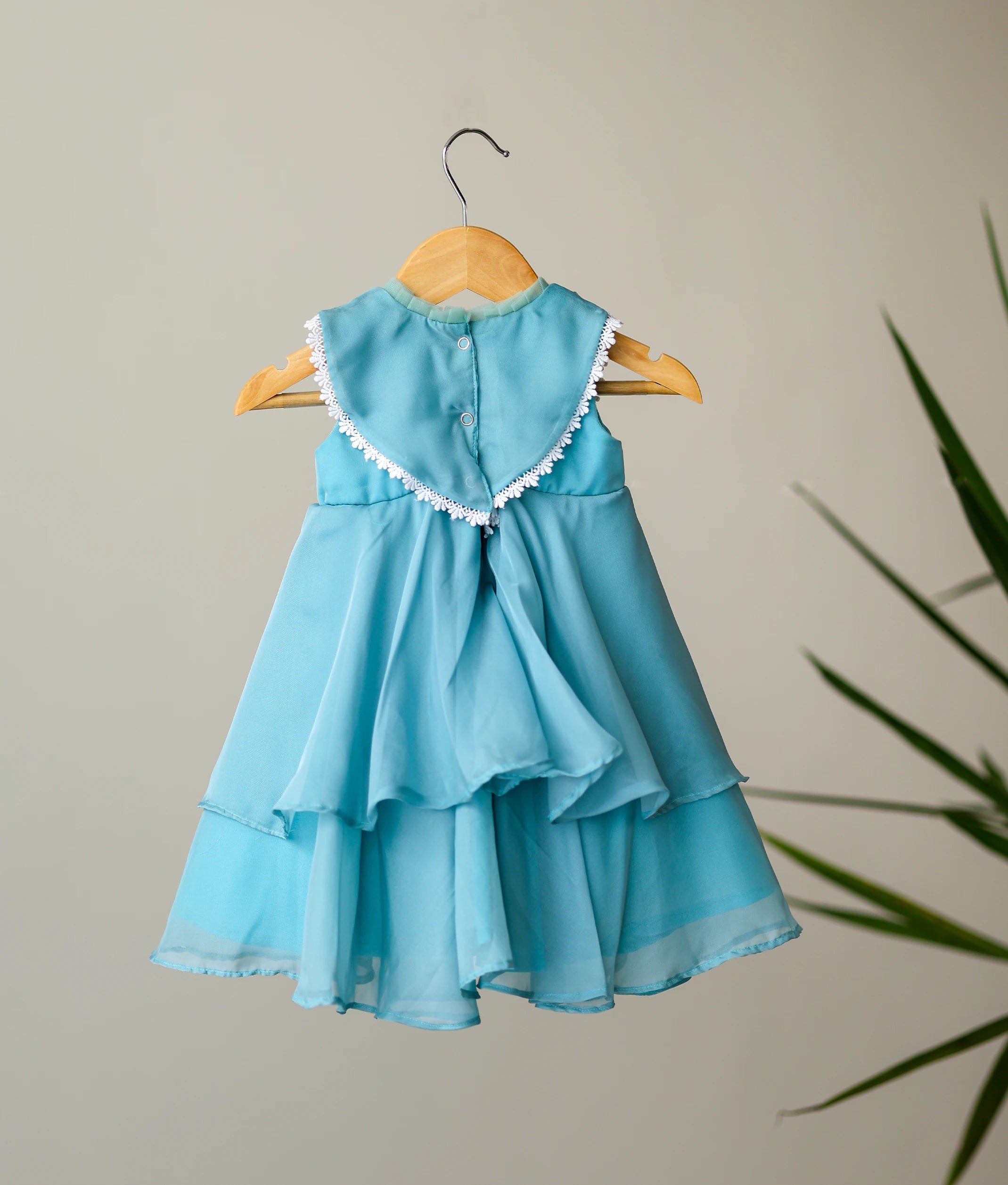Back view of pastel blue frock showing the square neck design, press button closure, and tiered organza layers