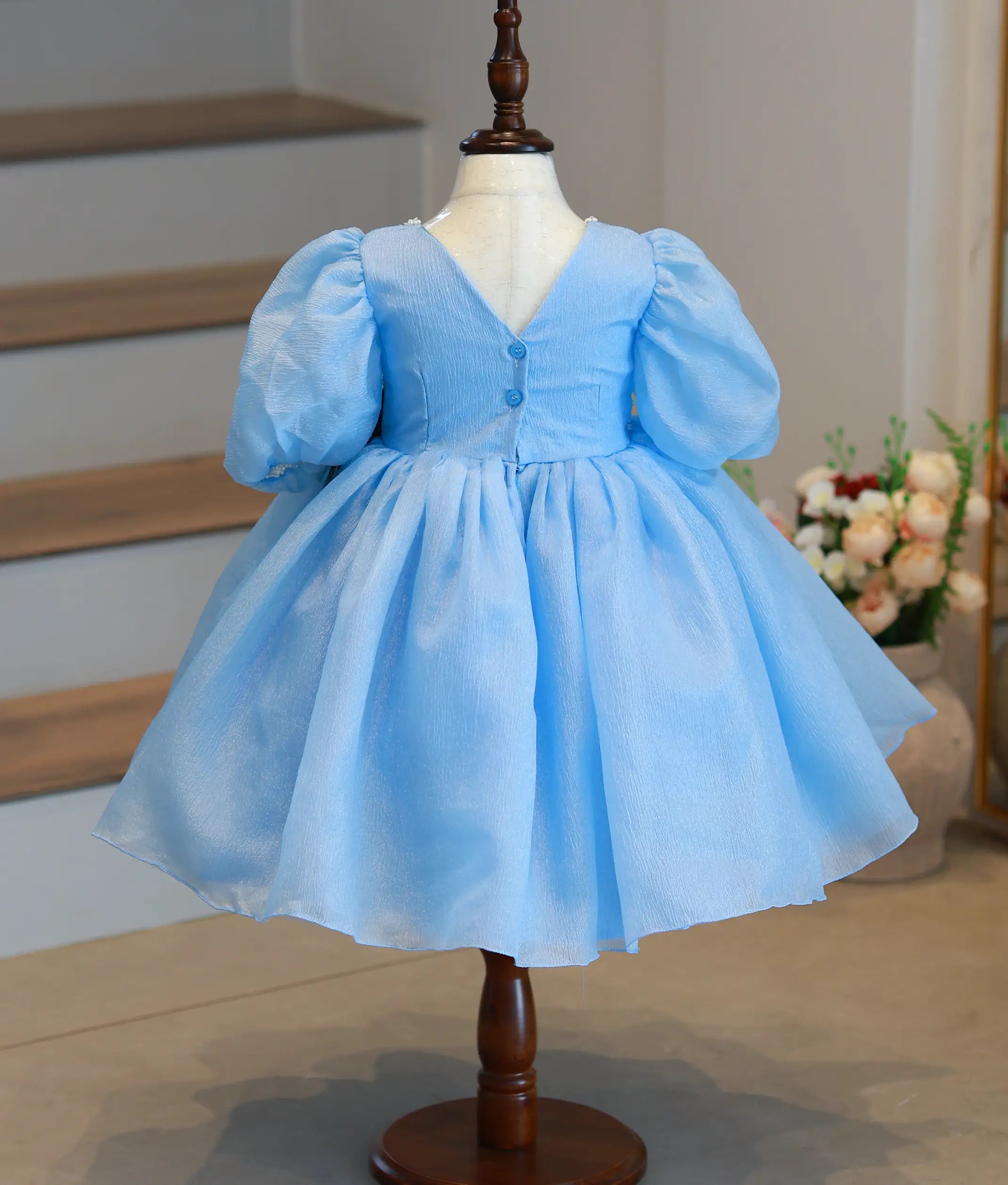 Back view of pastel blue frock showing the V-neck design and shirt button closure