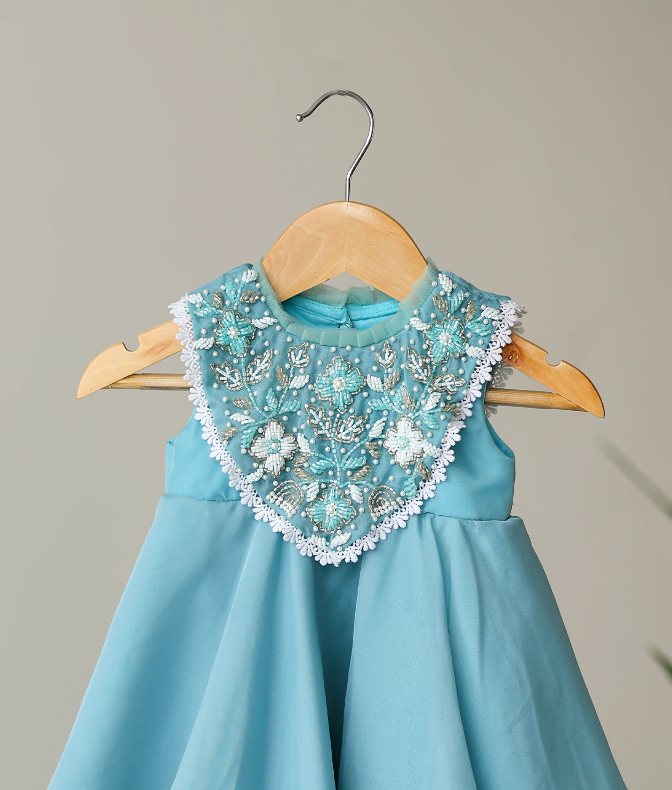 Close-up of the intricate hand-beaded floral yoke and white lace trim on the pastel blue butter organza birthday dress