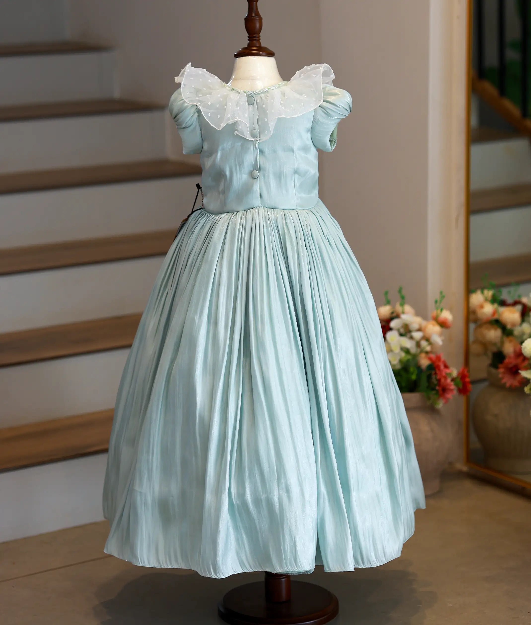 Back view of pastel green laser organza handworked gown showing the round neckline and show button closure