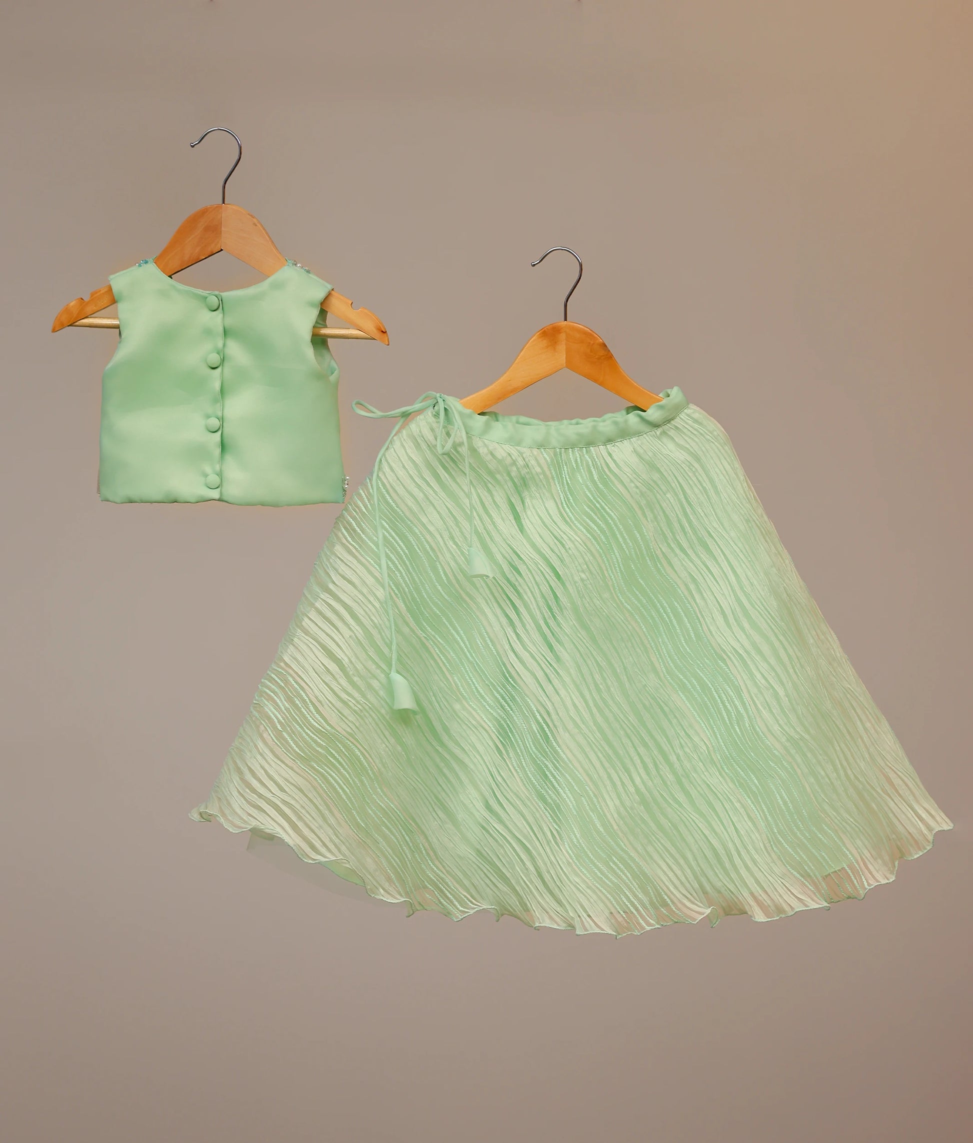 Back view of baby girl pastel green organza set showing the round neck and layered tuck organza bottom