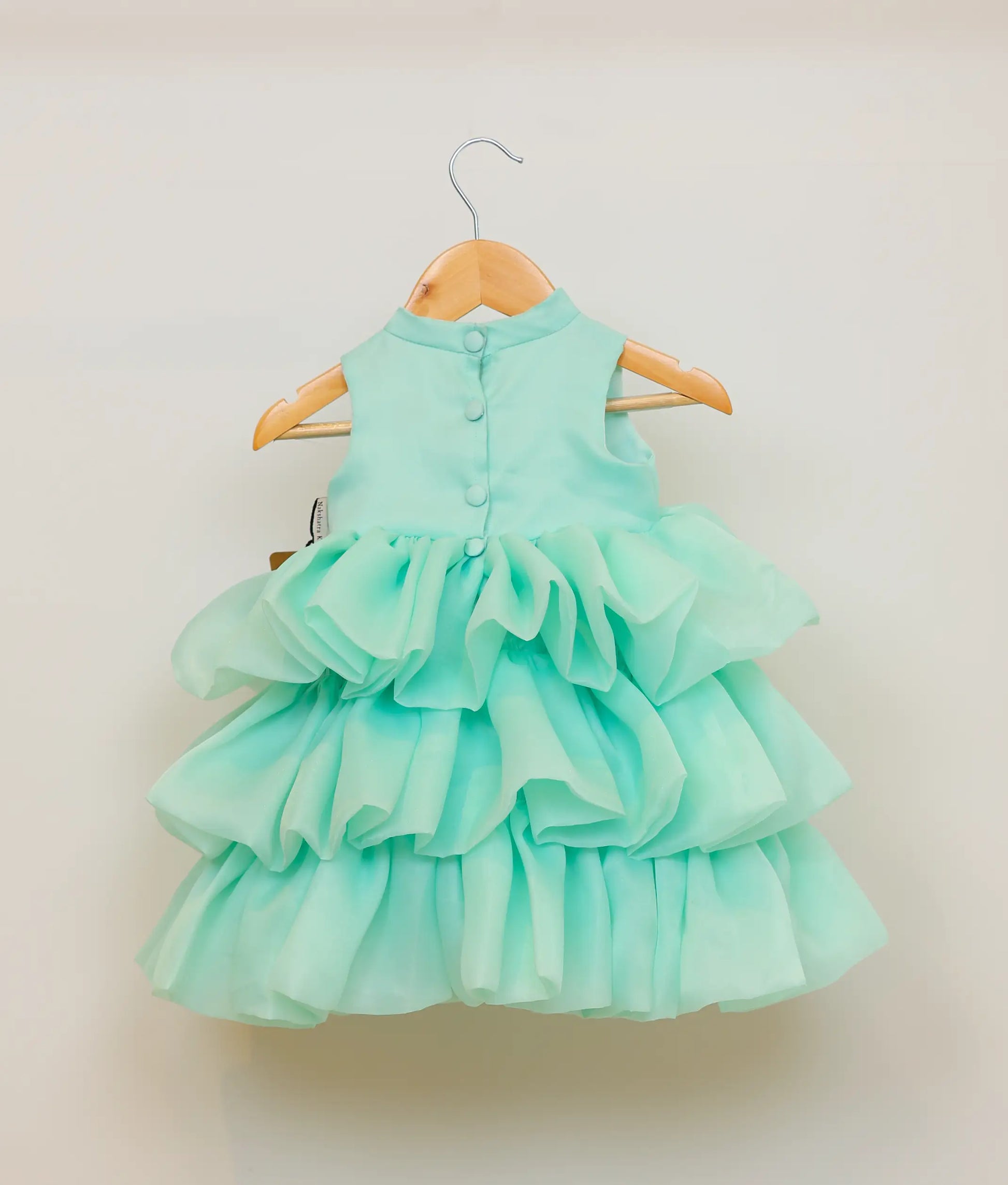 Back view of pastel green organza step dress showing the halter-neck closure and the layered texture of the below-knee skirt
