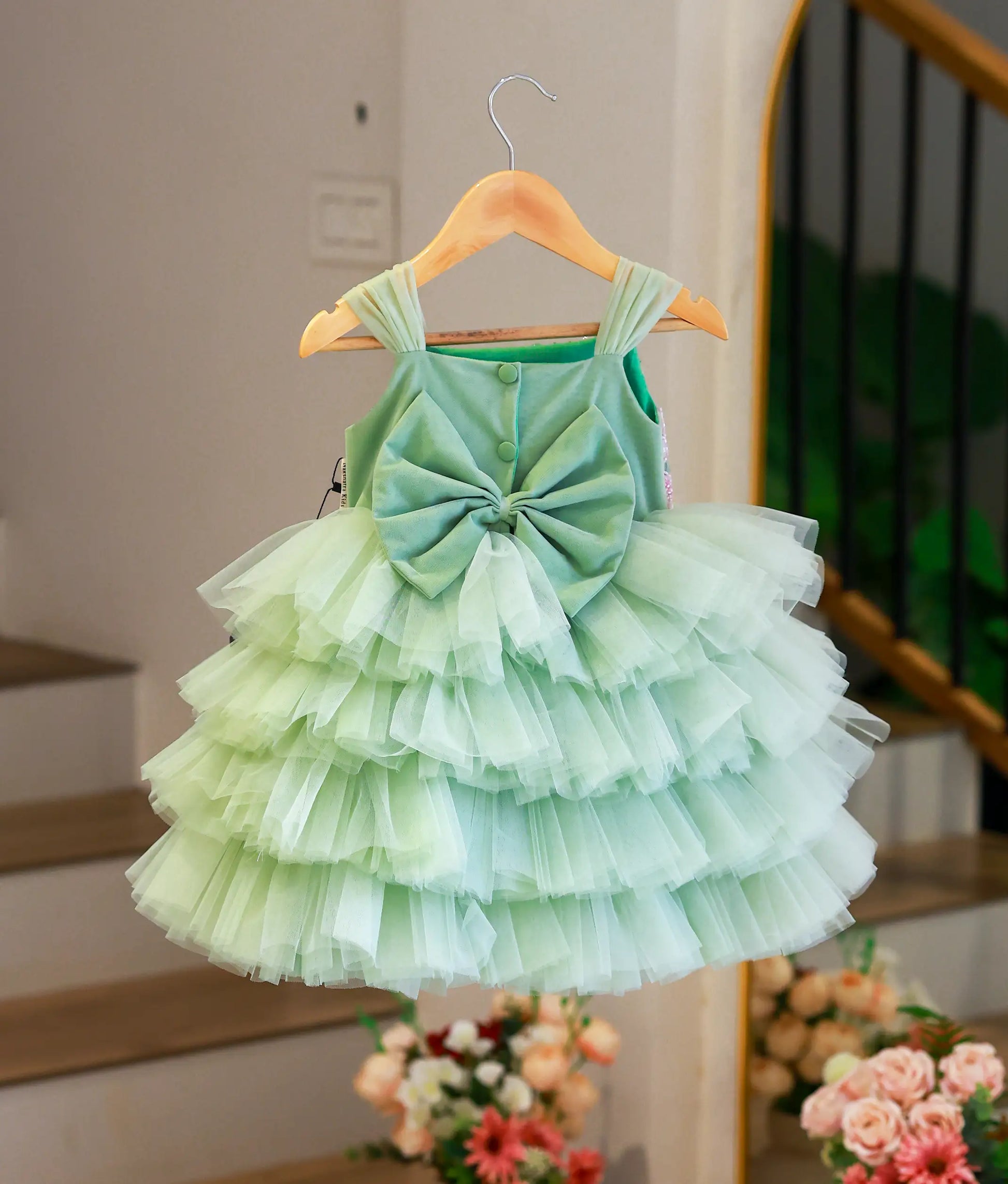 Back view of the pastel green party frock showing the large decorative bow and the voluminous layered tulle steps.