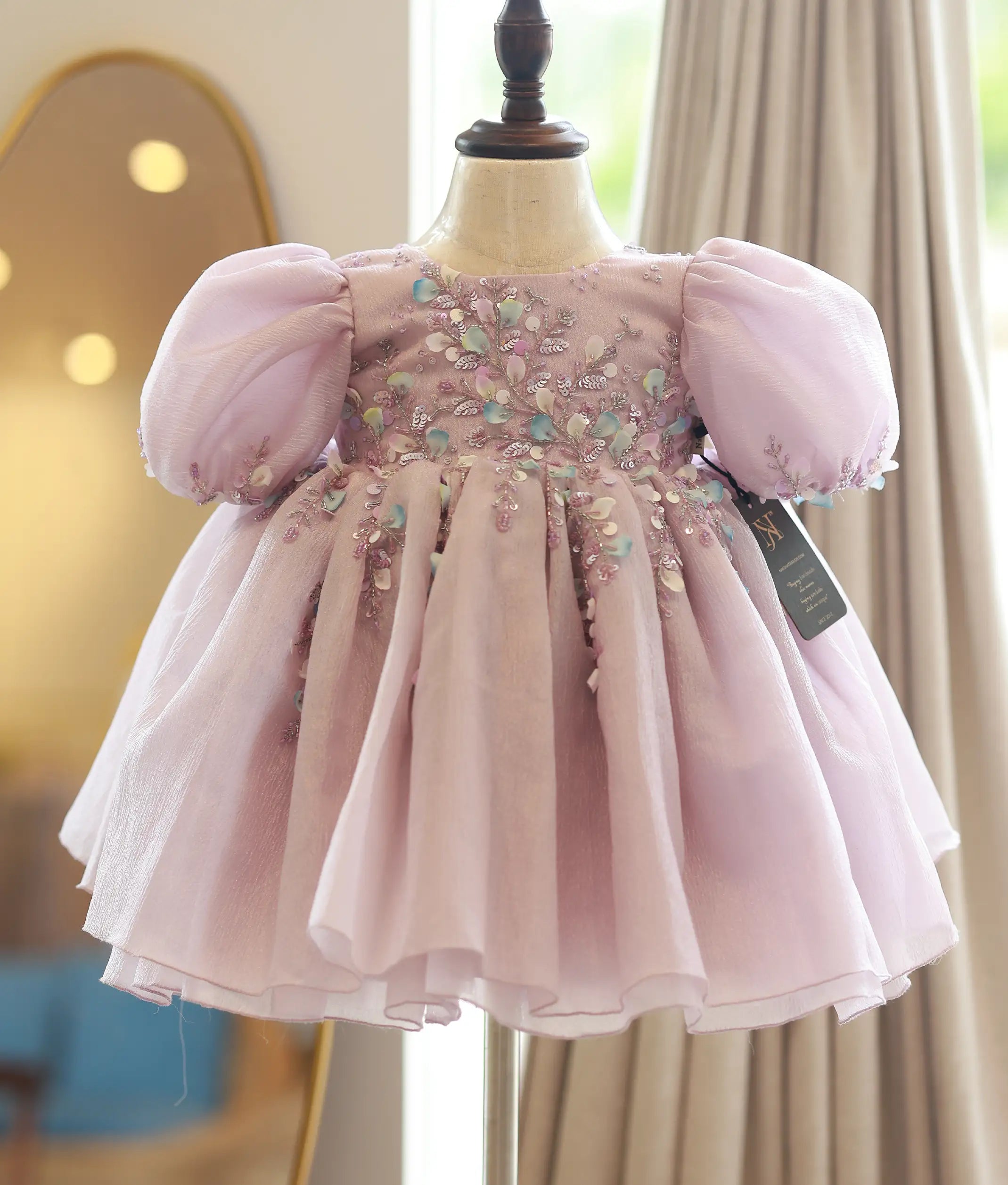 Front view of a pastel lavender crush organza flower girl frock with handworked floral patterns and balloon sleeves