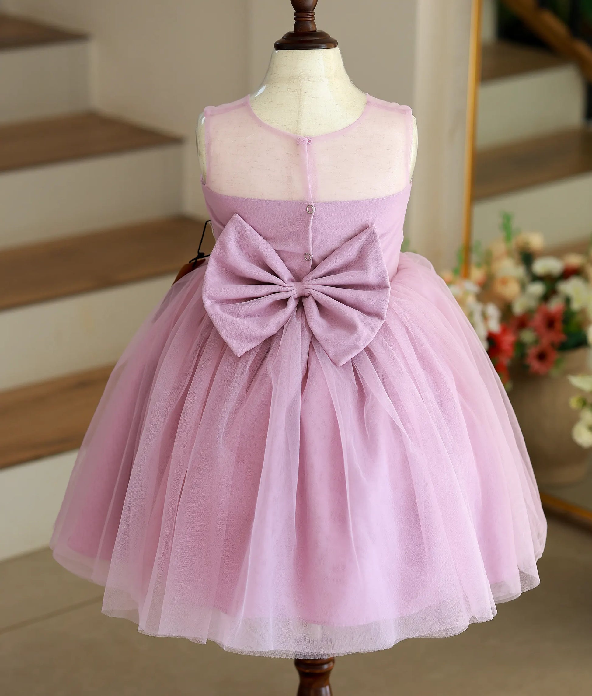 Back view of the pastel lavender frock showing the transparent neckline, buttons, and back bow.