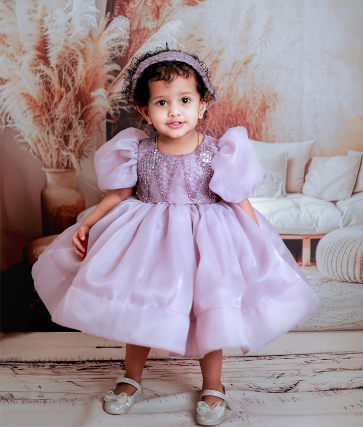 Baby girl wearing a pastel lavender organza birthday frock with balloon sleeves and a fancy worked yoke