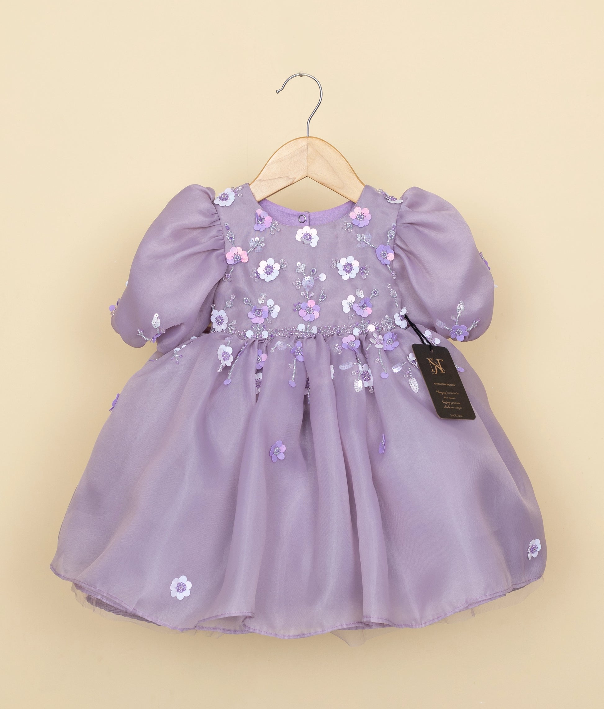 Front view of a pastel lavender organza girl's birthday frock with floral embroidery, beads, and balloon sleeves